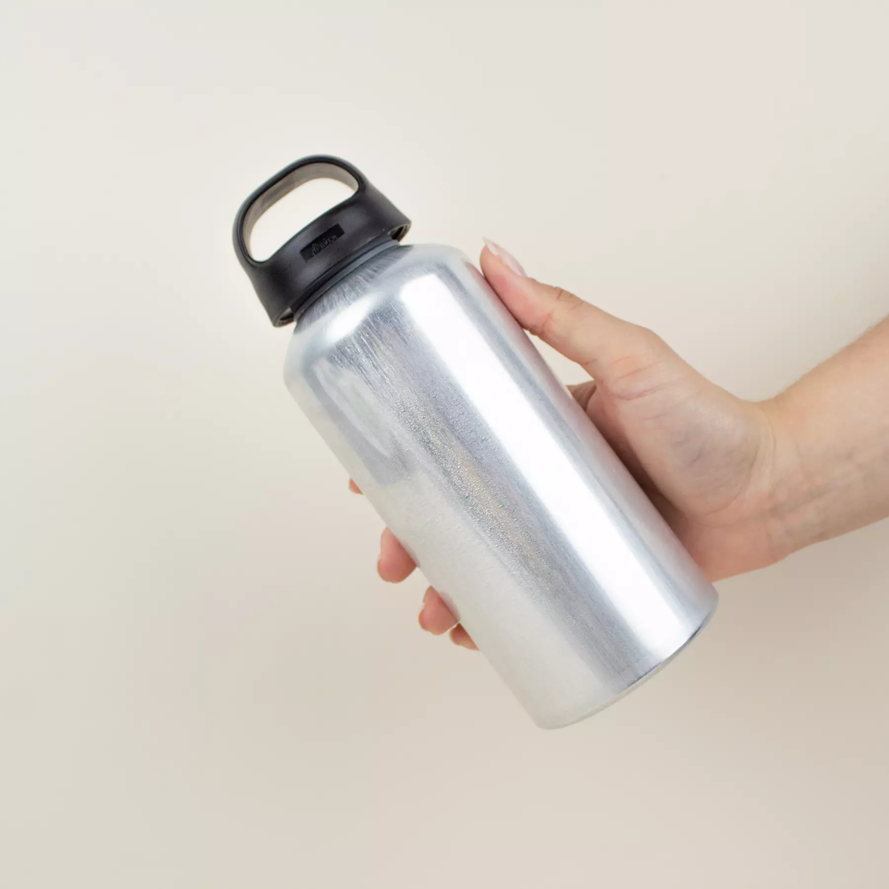 Mano sujetando una botella de agua reutilizable de aluminio reciclado