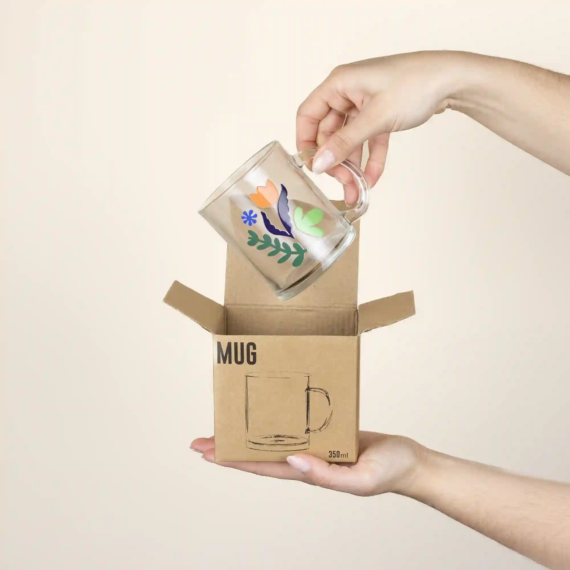 Manos sacando una taza de cristal personalizada de una caja de cartón