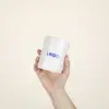 Taza de cerámica CANDELA Mano mostrando una taza de cerámica blanca con puntos negros personalizada con la palabra logo en azul