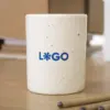Taza de cerámica CANDELA Taza de cerámica blanca con puntos negros personalizada con logo azul sobre una mesa de madera