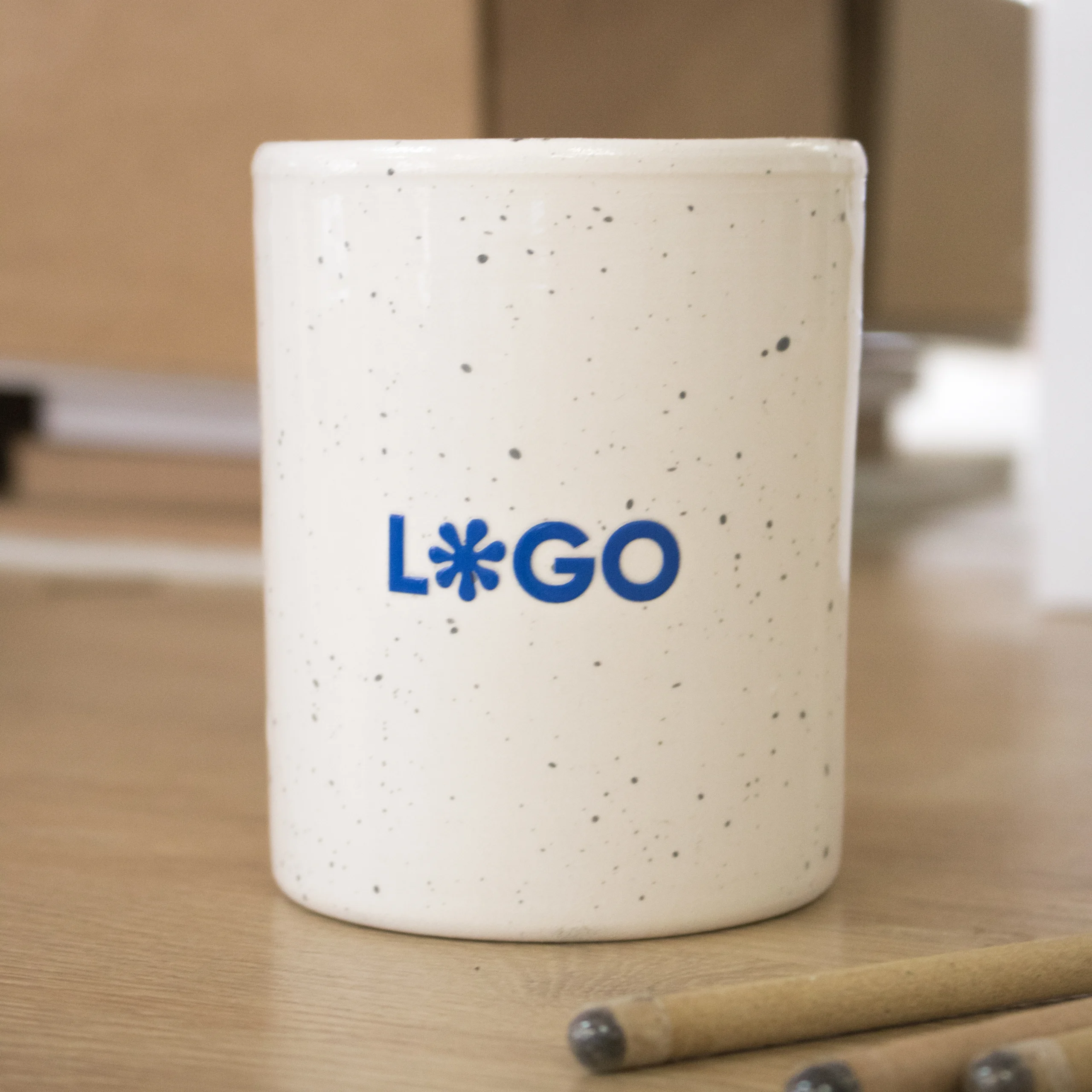 Taza de cerámica CANDELA Taza de cerámica blanca con puntos negros personalizada con logo azul sobre una mesa de madera