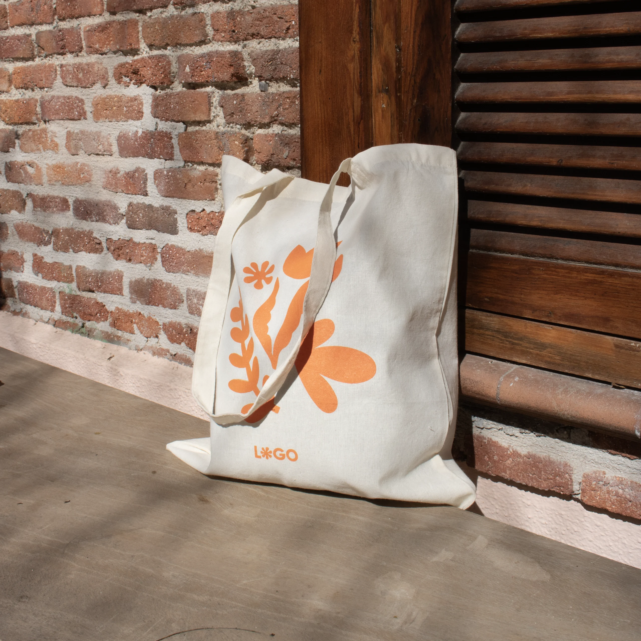 Bolsa de algodón personalizada NATA 140 Bolsa de algodón personalizada con un diseño naranja apoyada en el suelo