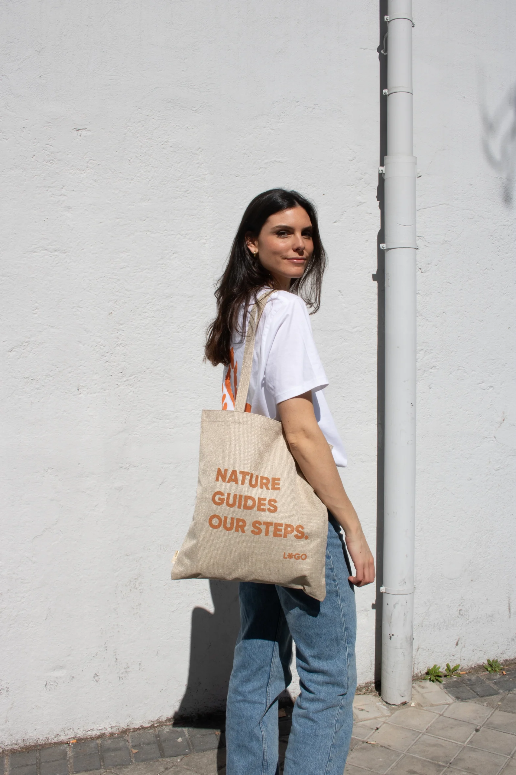 Chica paseando en la calle con bolsa de cáñamo personalizada con logo naranja