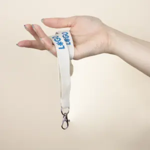 Lanyards sostenibles de algodón orgánico con logo azul modelo mano fondo beige