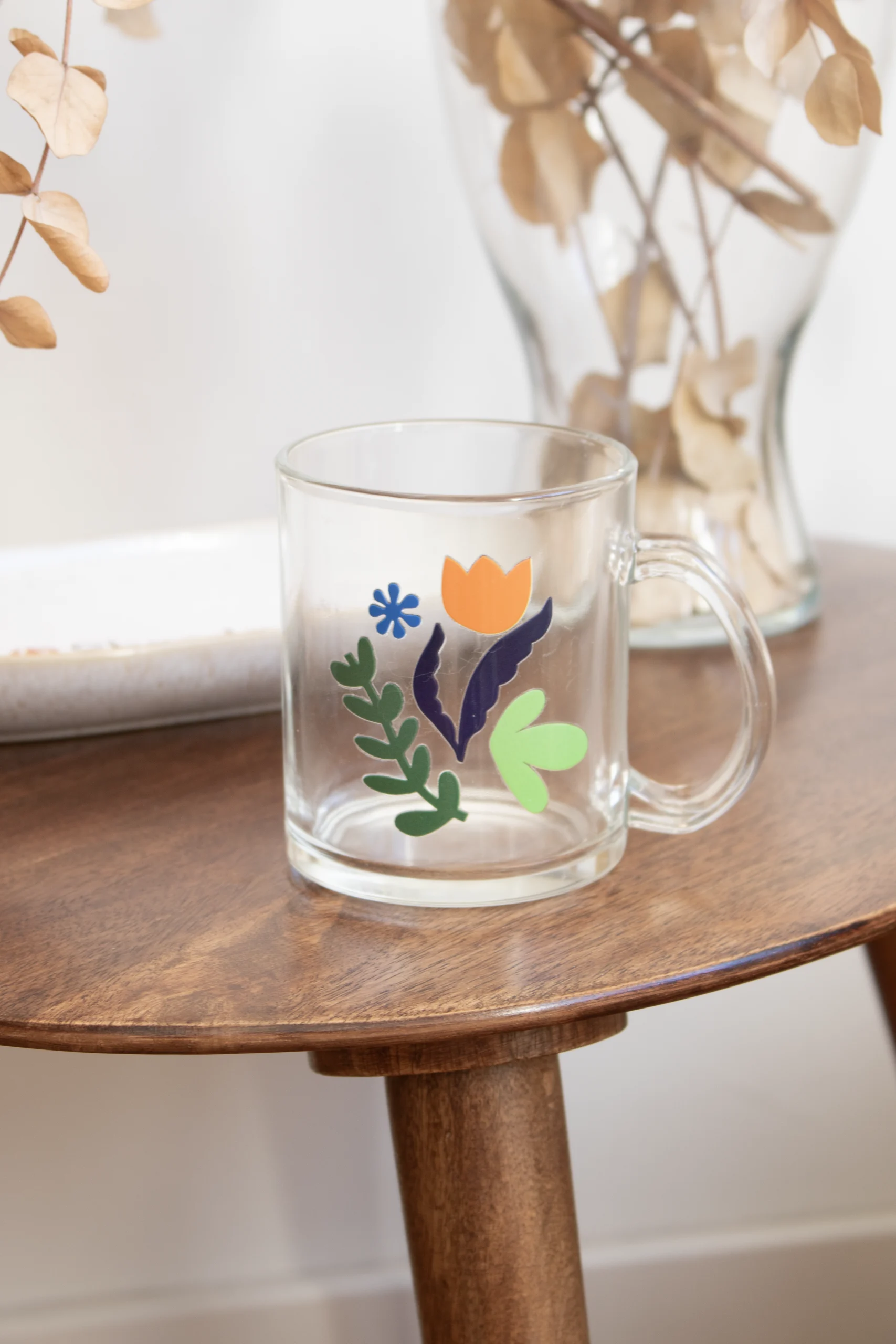 Taza de cristal con asa personalizada sobre una mesa de madera