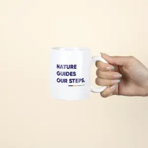 Taza Blanca personalizada con logo azul modelo mano sobre fondo beige