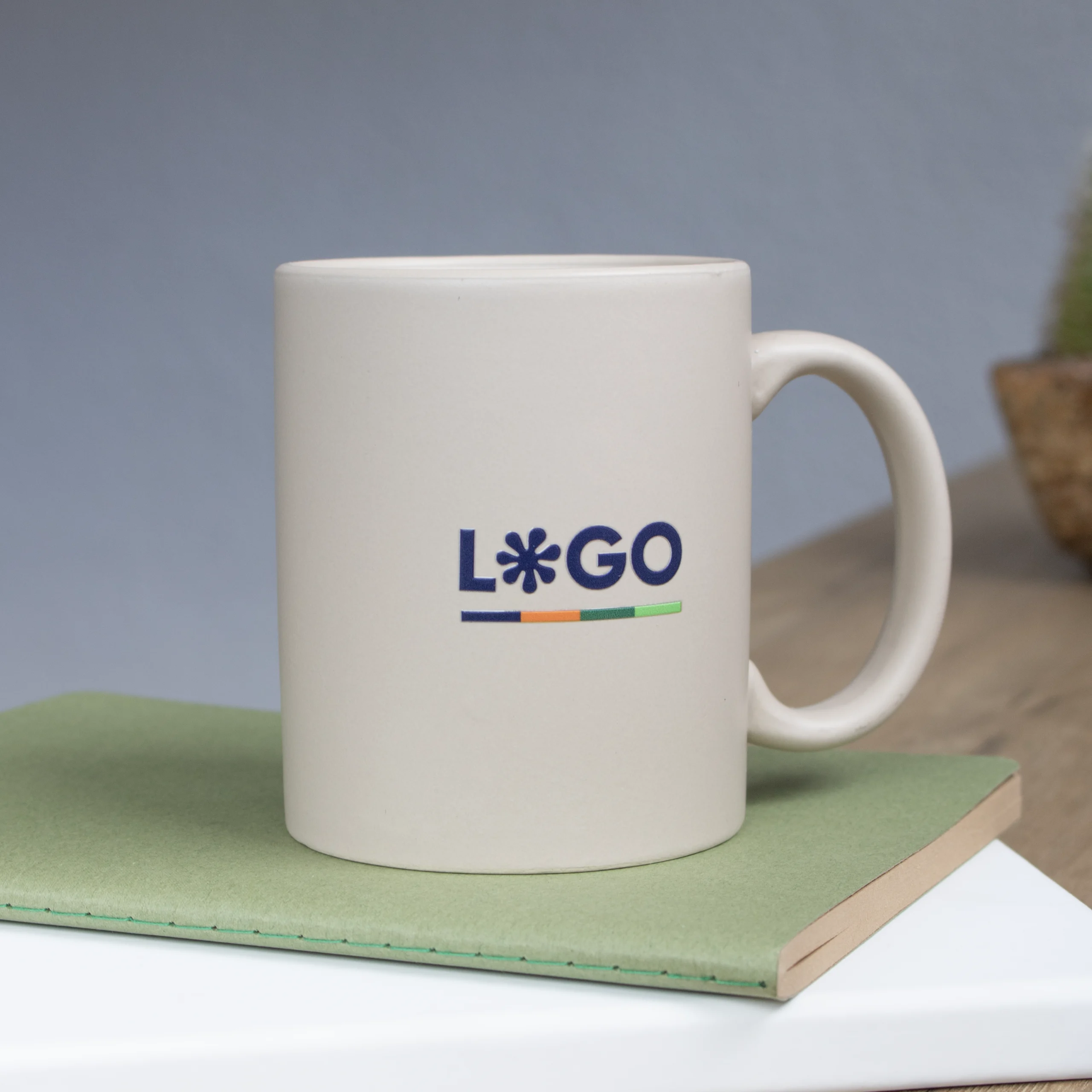 Taza beige con logo personalizado a todo color y cuaderno verde