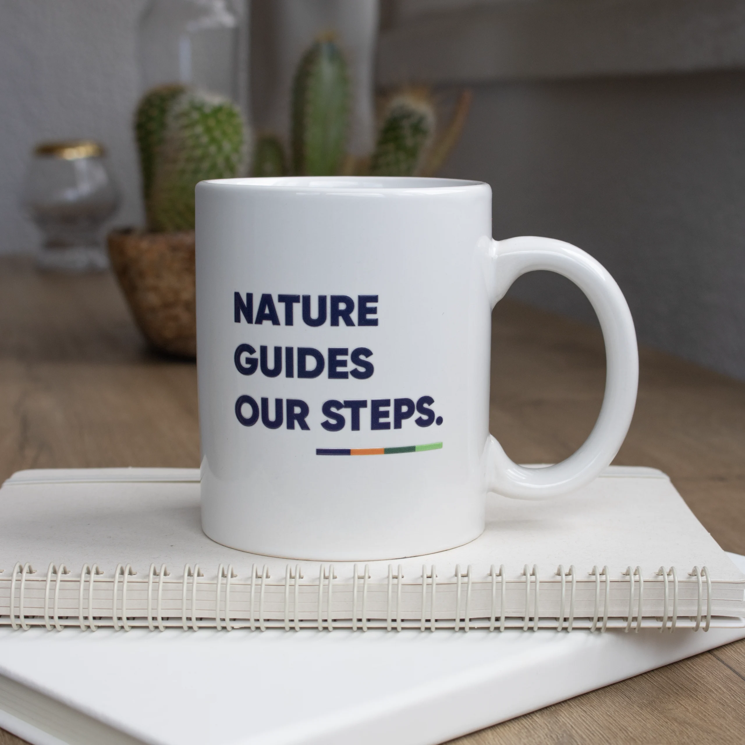 Taza Blanca para personalizar con logo azul frontal sobre cuaderno blanco