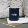 Vaso térmico con asa azul con logo blanco apoyada en cuadernos