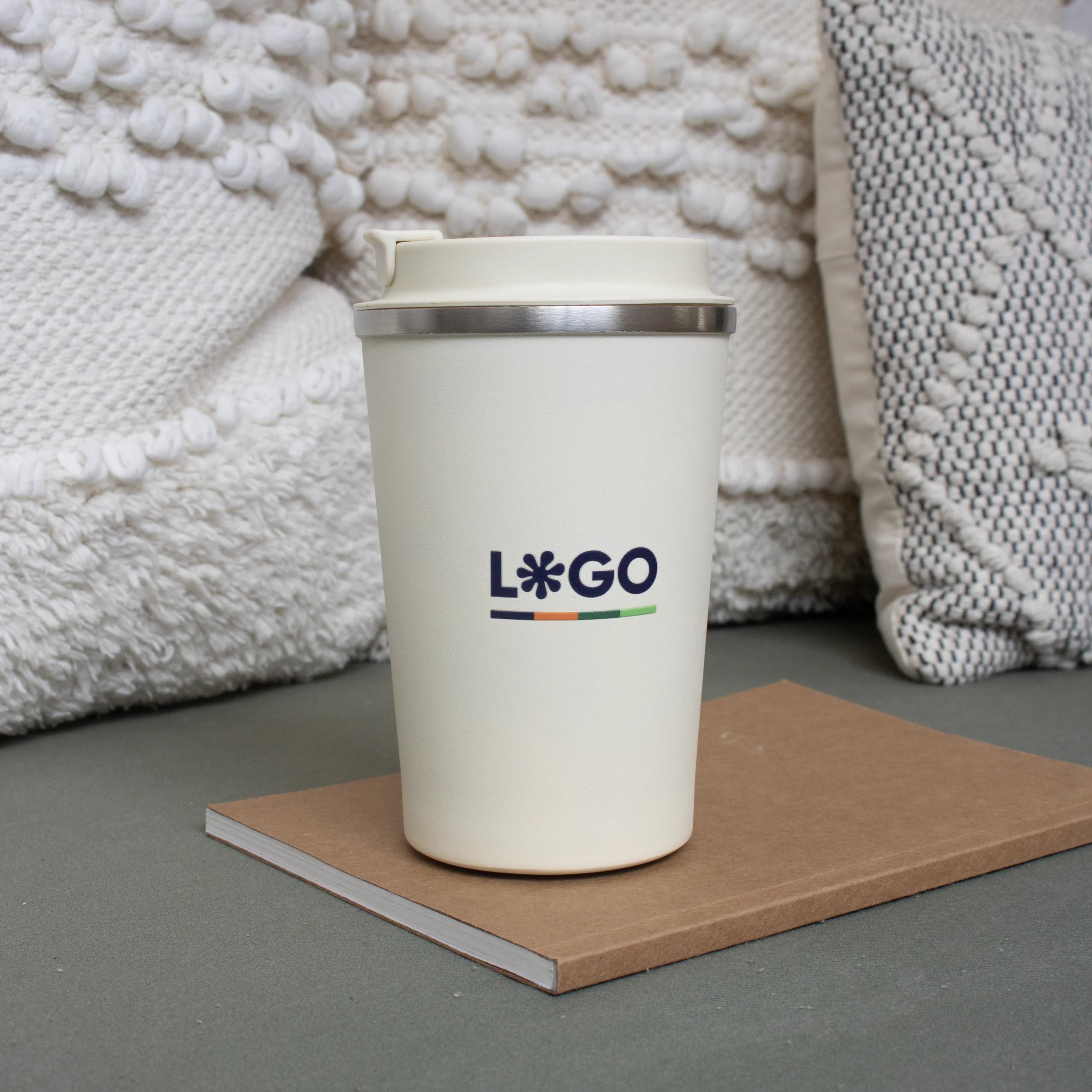 Taza térmica con tapa beige y cuaderno marrón