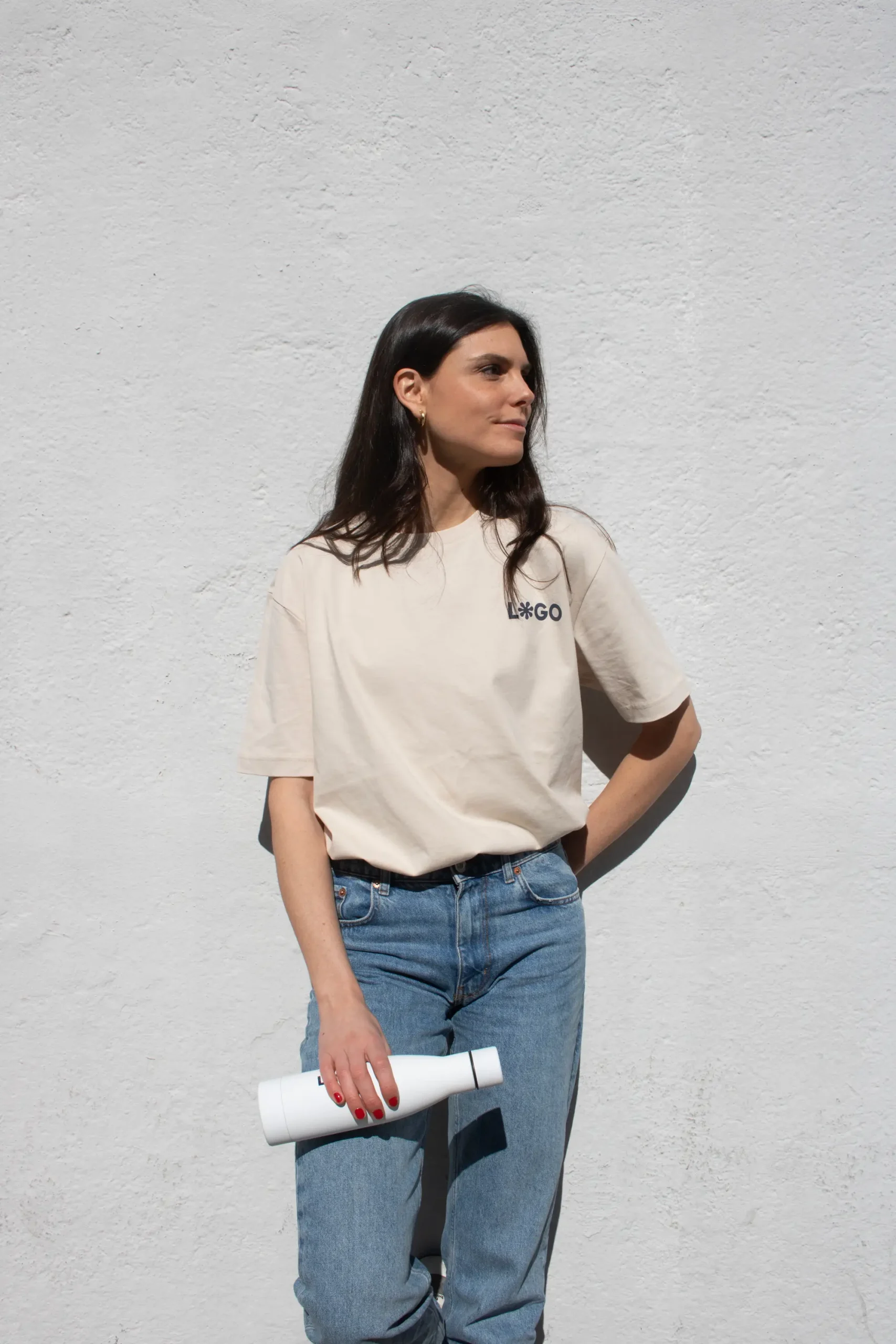 Camiseta orgánica color Beige con logro modelo chica apoyada en pared