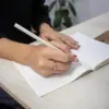 Lápiz de papel reciclado ALBAR En uso Lápiz de papel reciclado personalizado modelo mano chica escribiendo en cuaderno