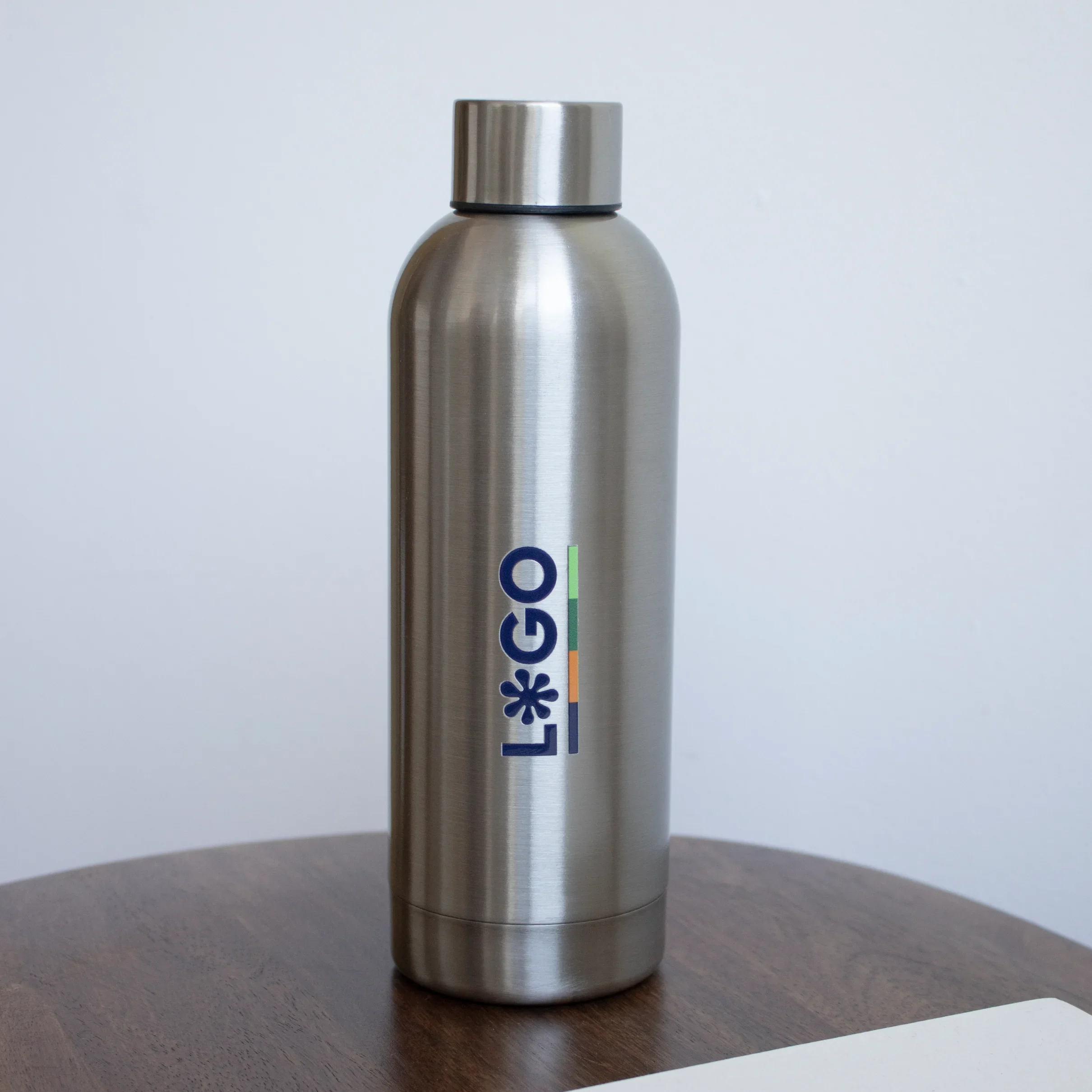 Botella acero inoxidable personalizada con logo sobre mesa de madera