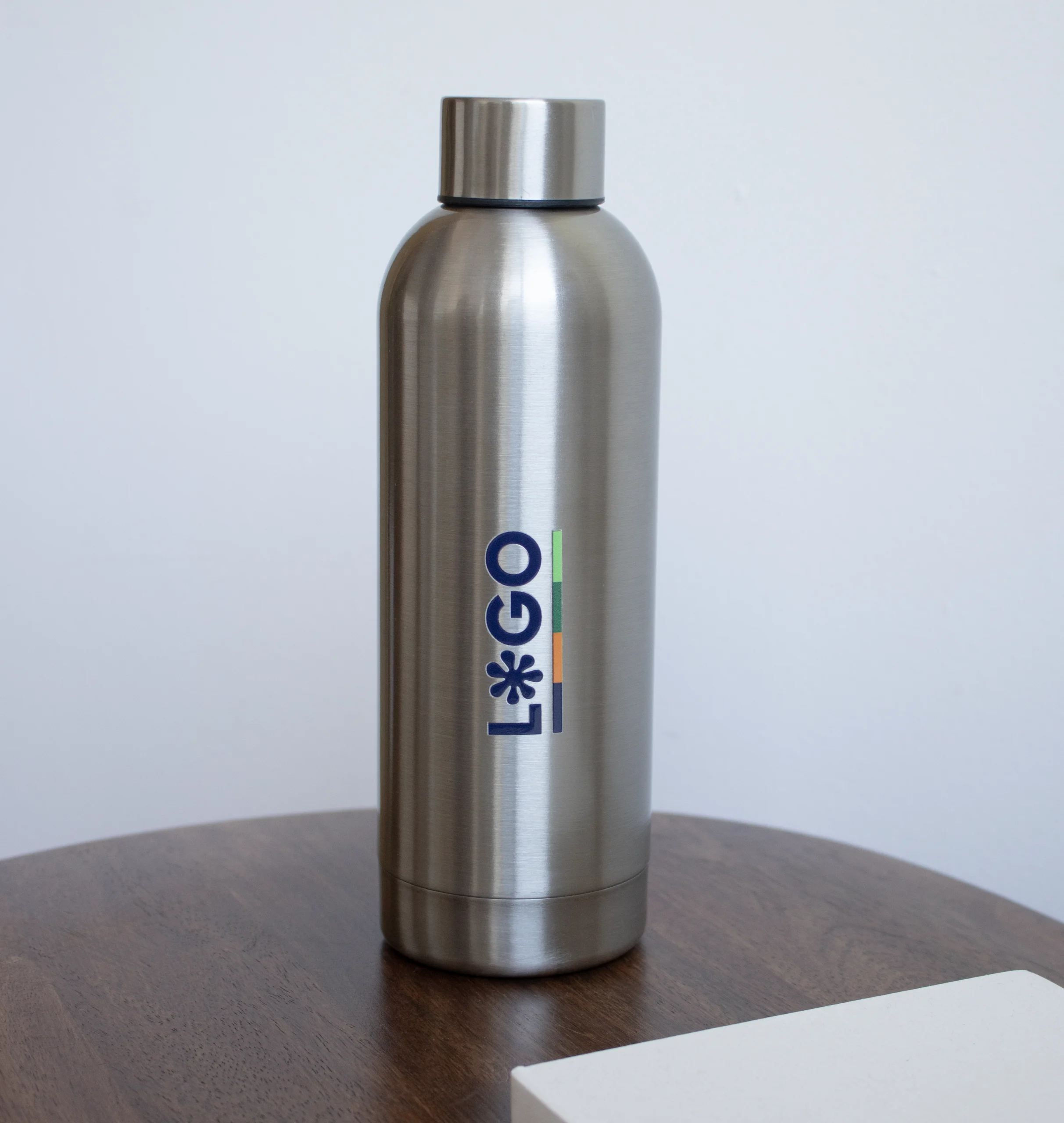Botella acero inoxidable personalizada con logo sobre mesa de madera