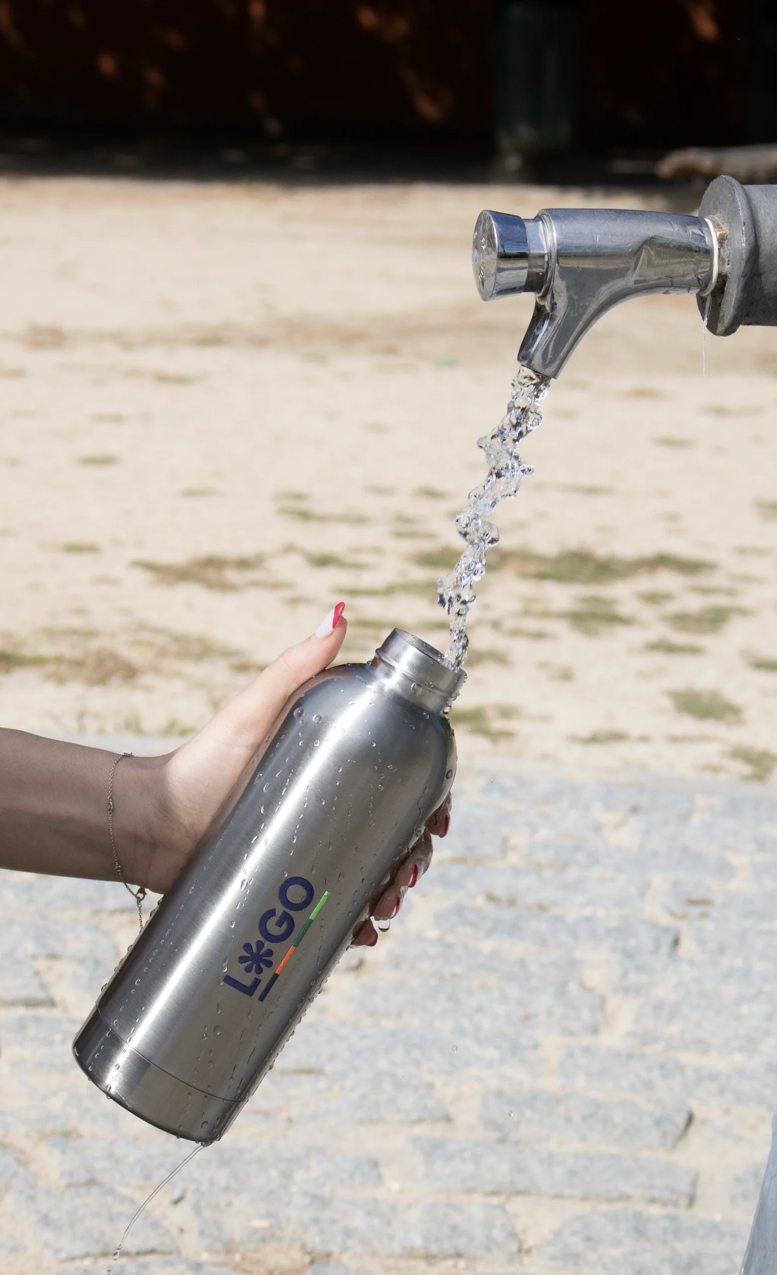 Botella acero inoxidable personalizada modelo mano debajo de fuente con agua