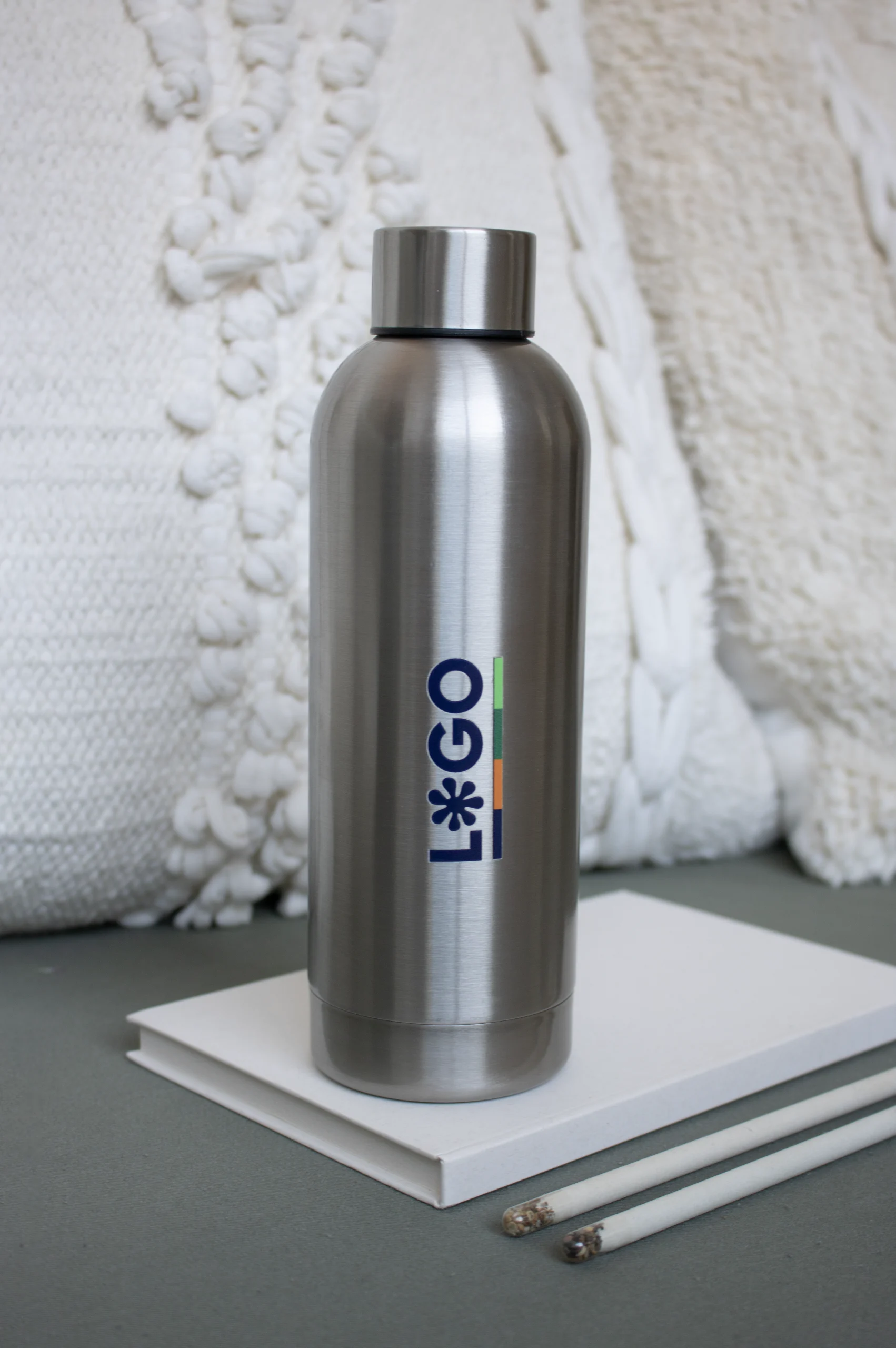 Botella acero inoxidable personalizada con cuaderno blanco lápices y cojín blanco