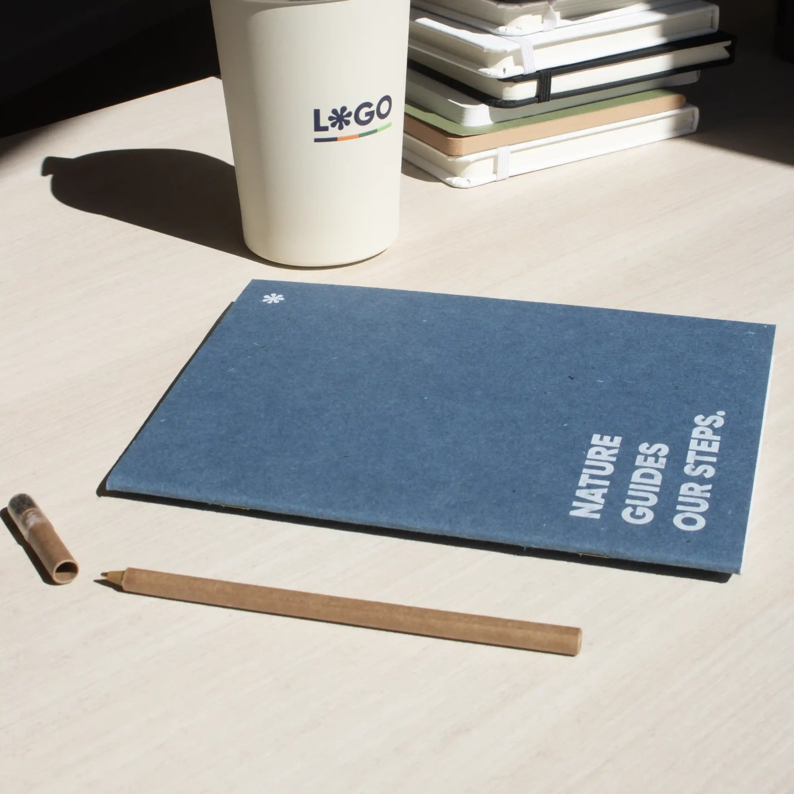 Cuaderno de grapa azul portada personalizada con texto blanco bolígrafo y taza