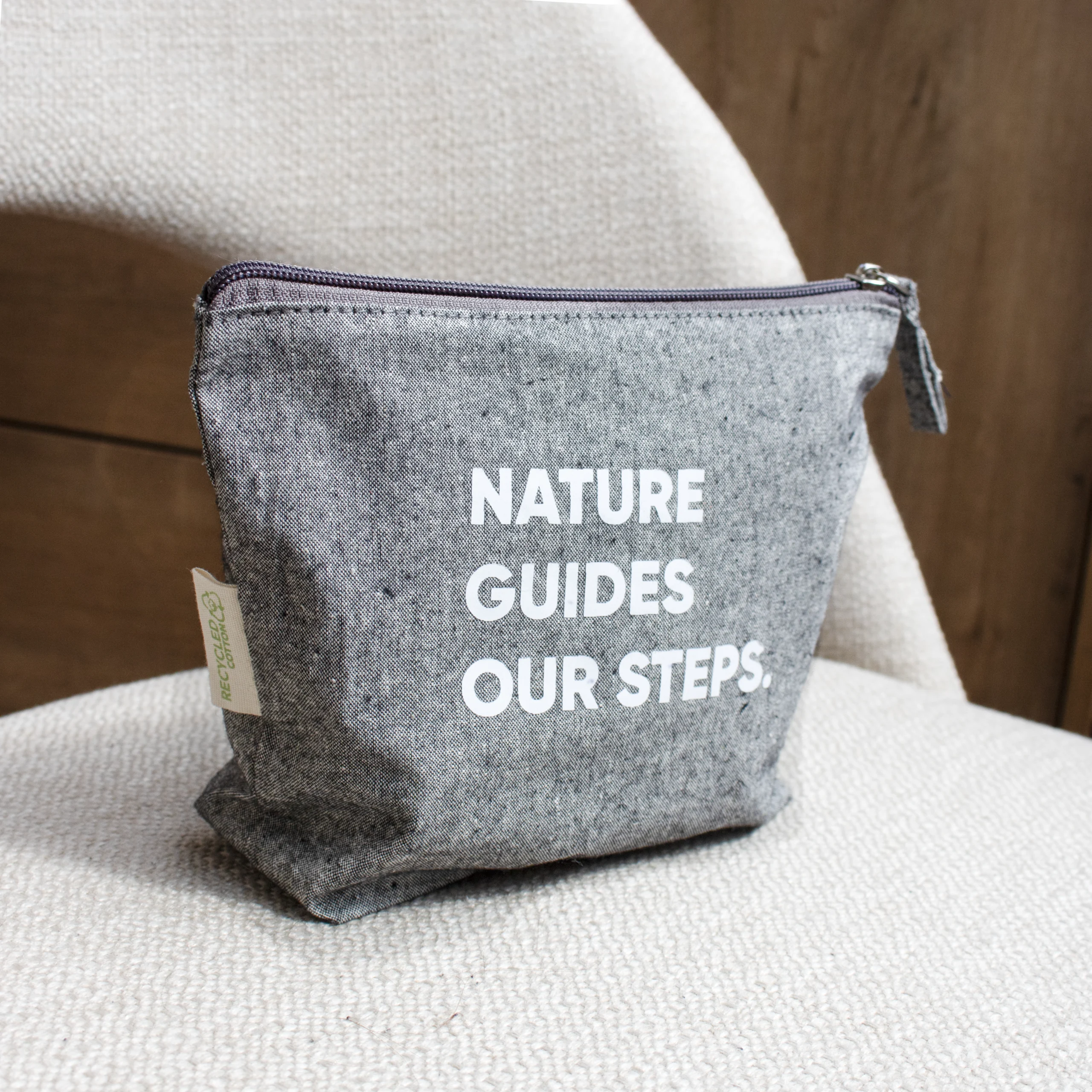 Trousse de toilette personnalisée en coton gris avec texte blanc sur chaise grise