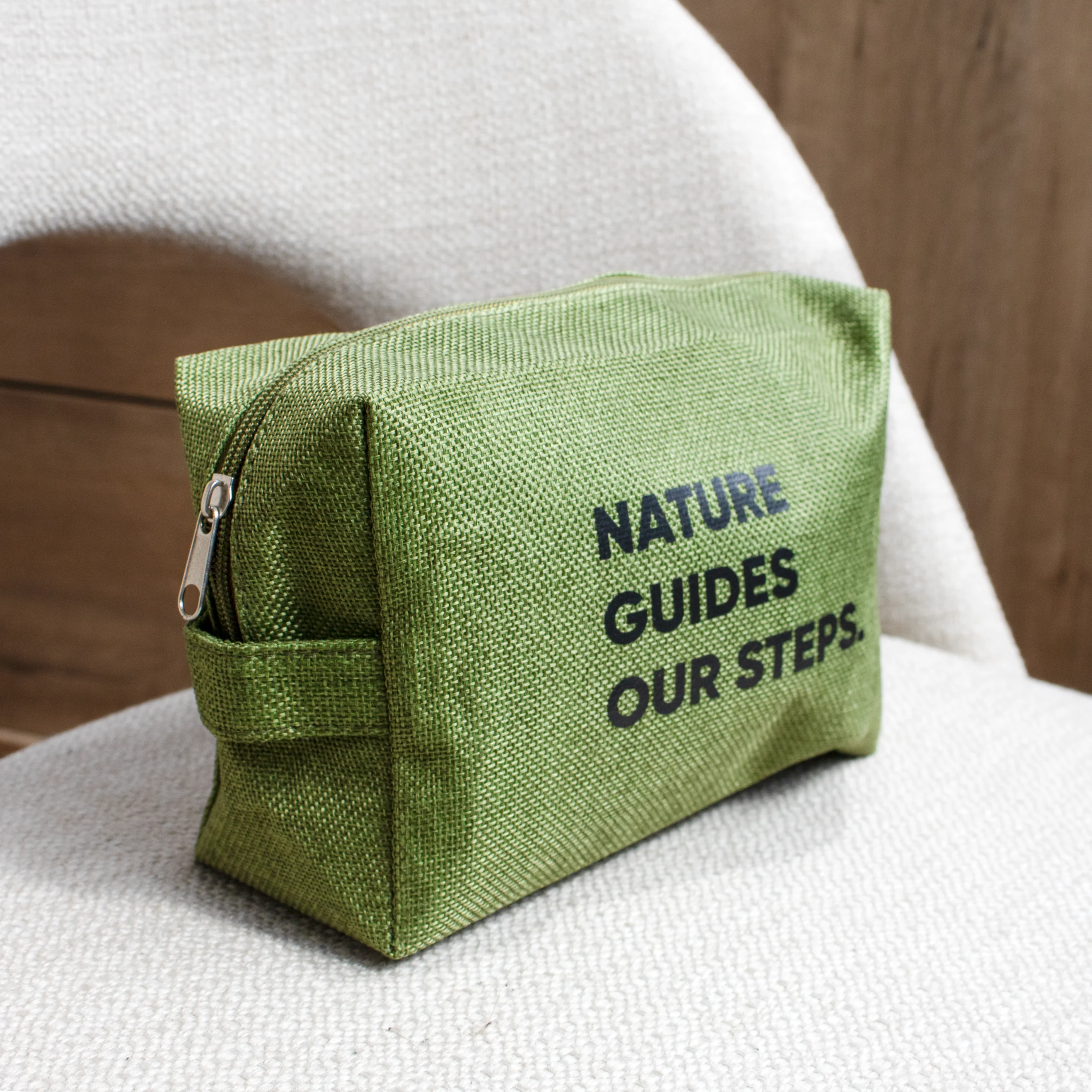 Neceser personalizado verde texto negro sobre silla beige