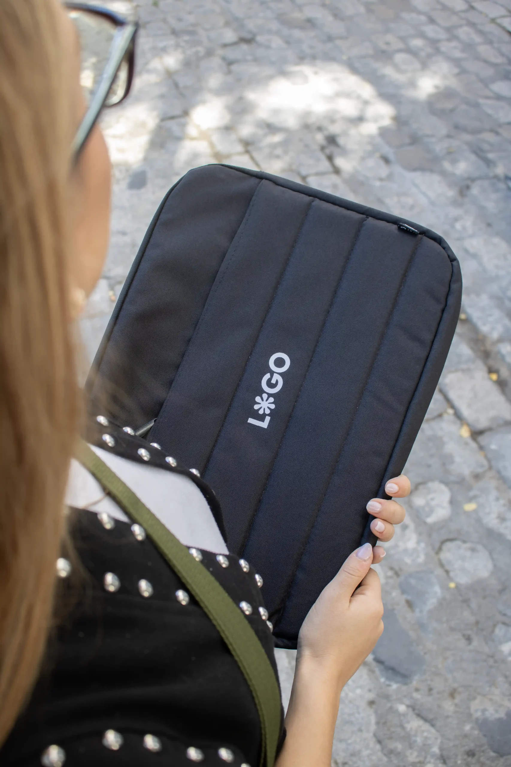 Funda portátil negra personalizada con logo blanco modelo chica fondo calle