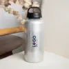 Botella de aluminio personalizada con la palabra logo colocada encima de un sofá beige