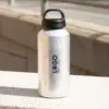 Botella de aluminio personalizada con la palabra logo apoyada en la calle