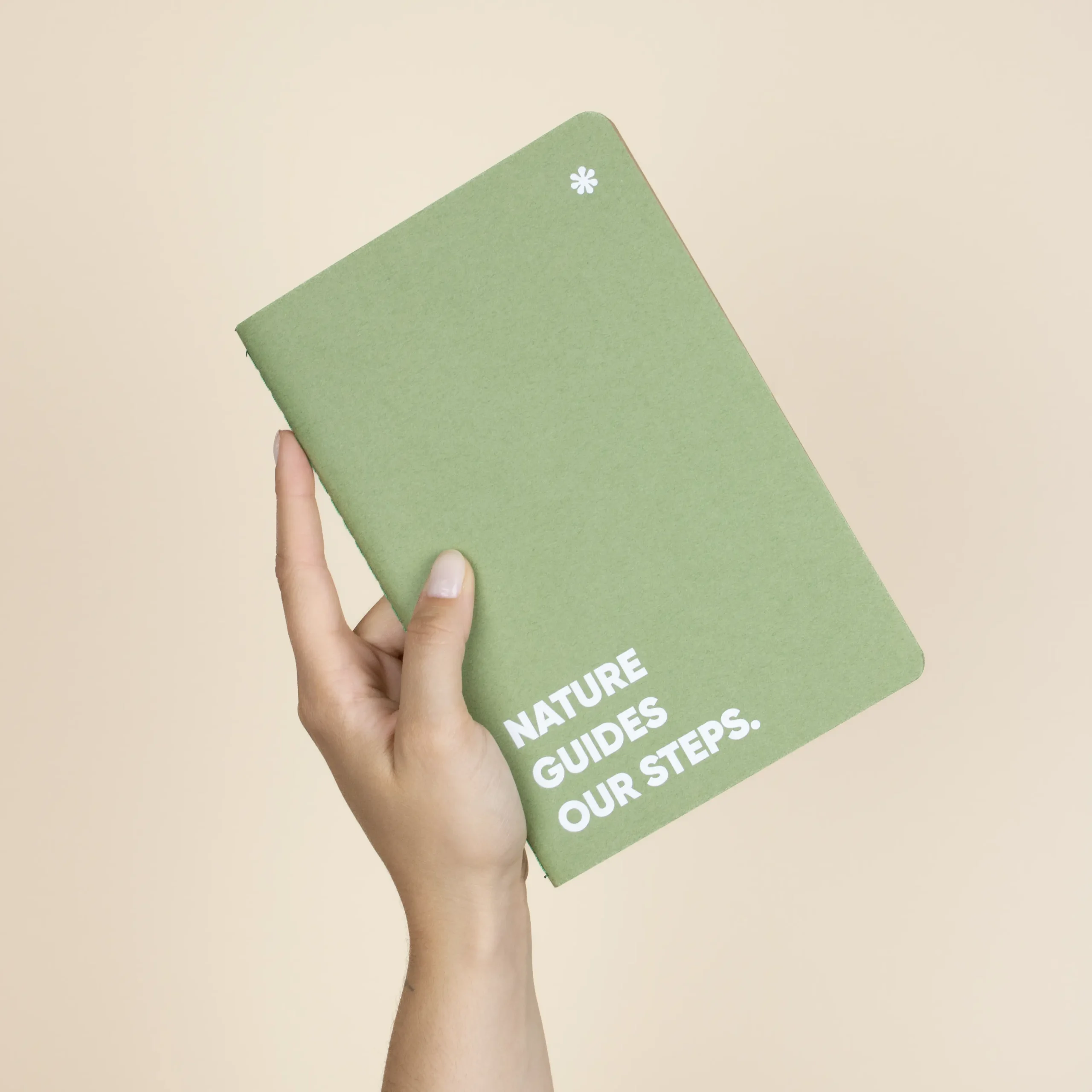 Cuaderno verde reciclado personalizado texto blanco modelo mano fondo beige