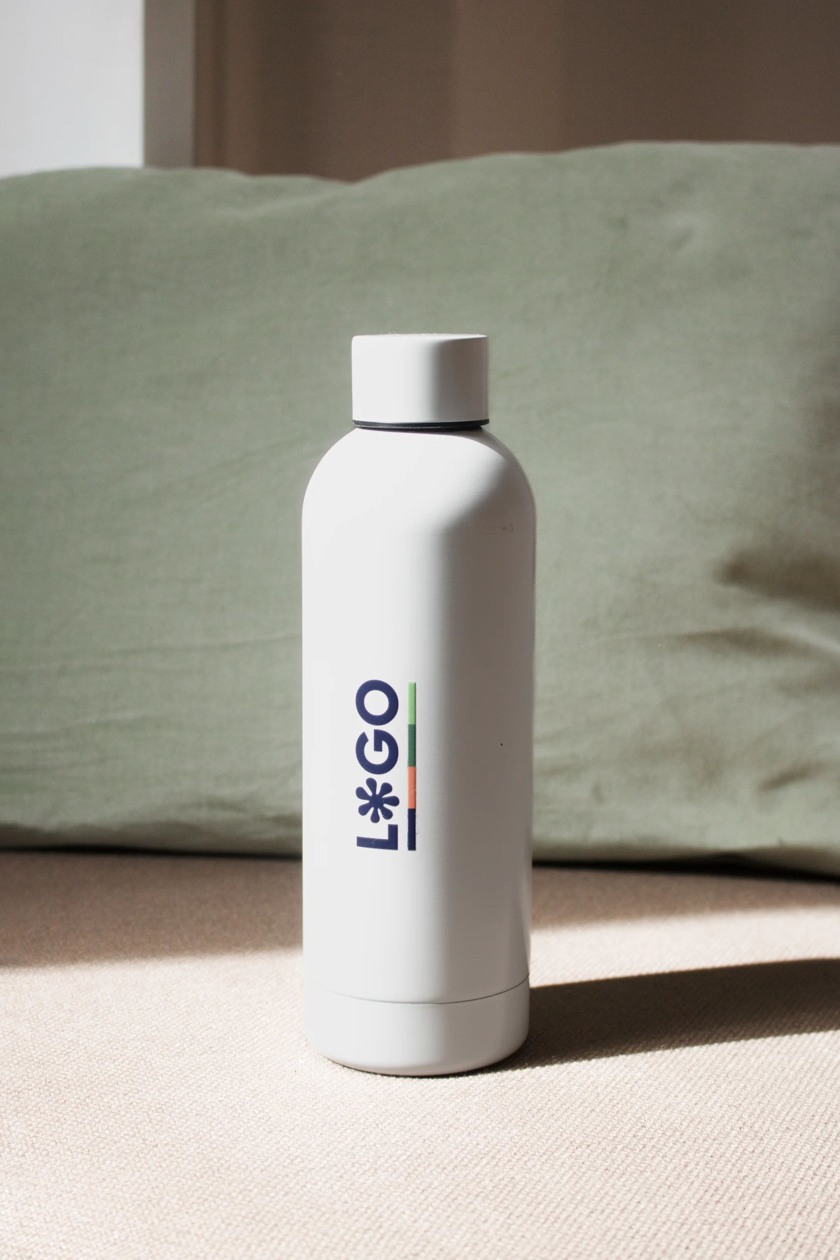 Botella térmica color blanco personalizada con logo fondo cojín verde