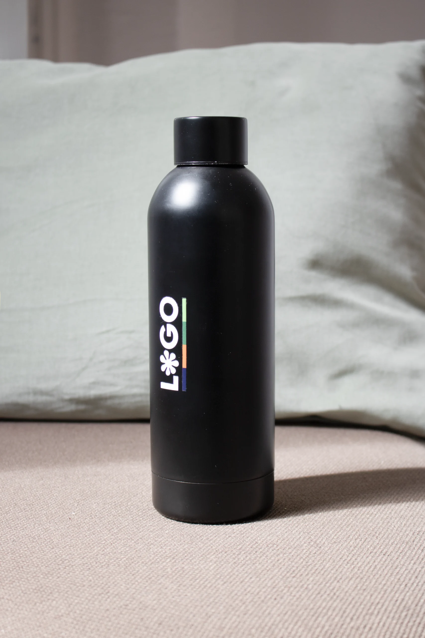 Botella térmica color negro personalizada con logo fondo cojín verde