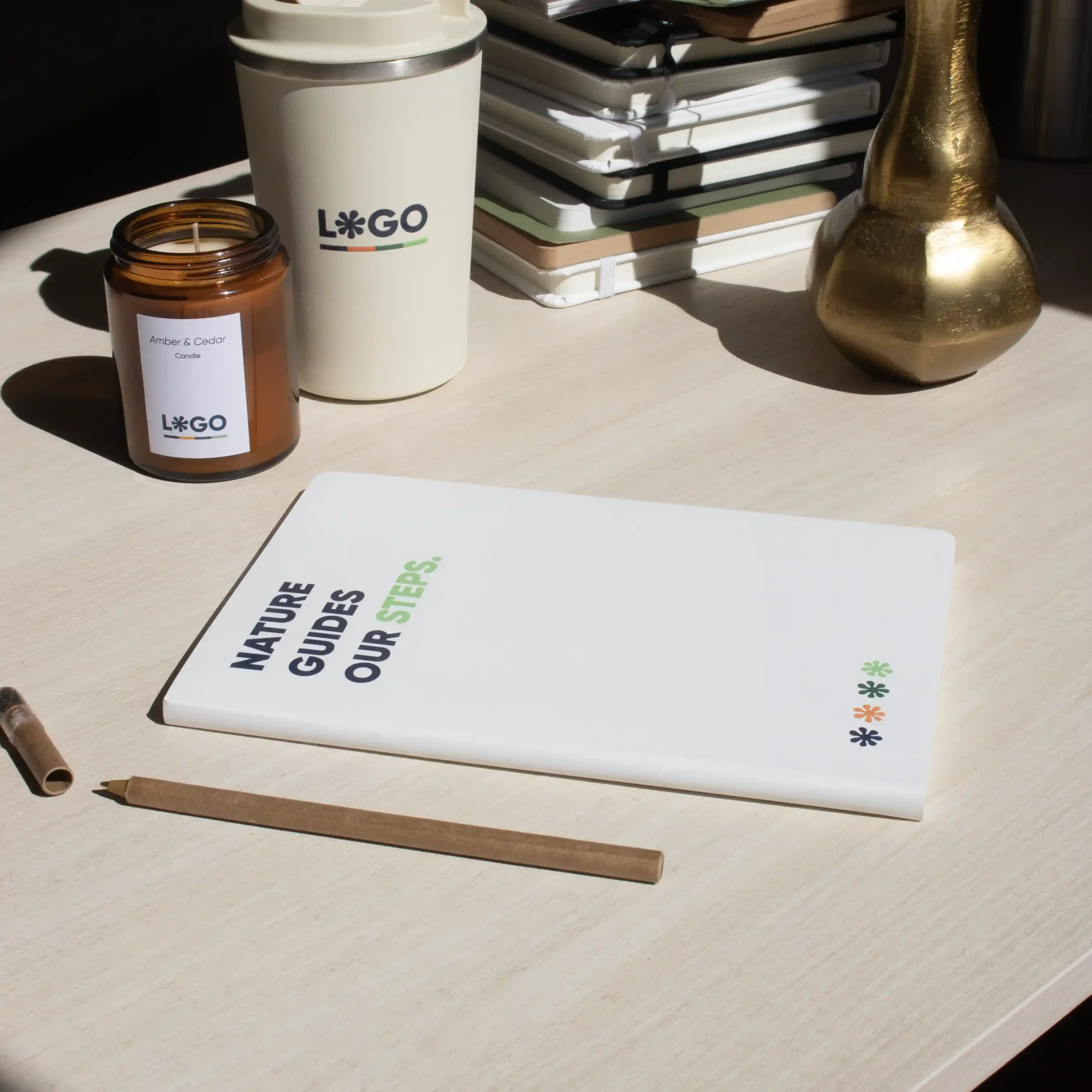 Mesa madera con cuaderno papel de piedra blanco personalizado, vela, taza y lapicero