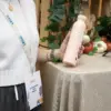 Chica sujetando una botella rosa de caña de azúcar personalizada en un evento de empresa
