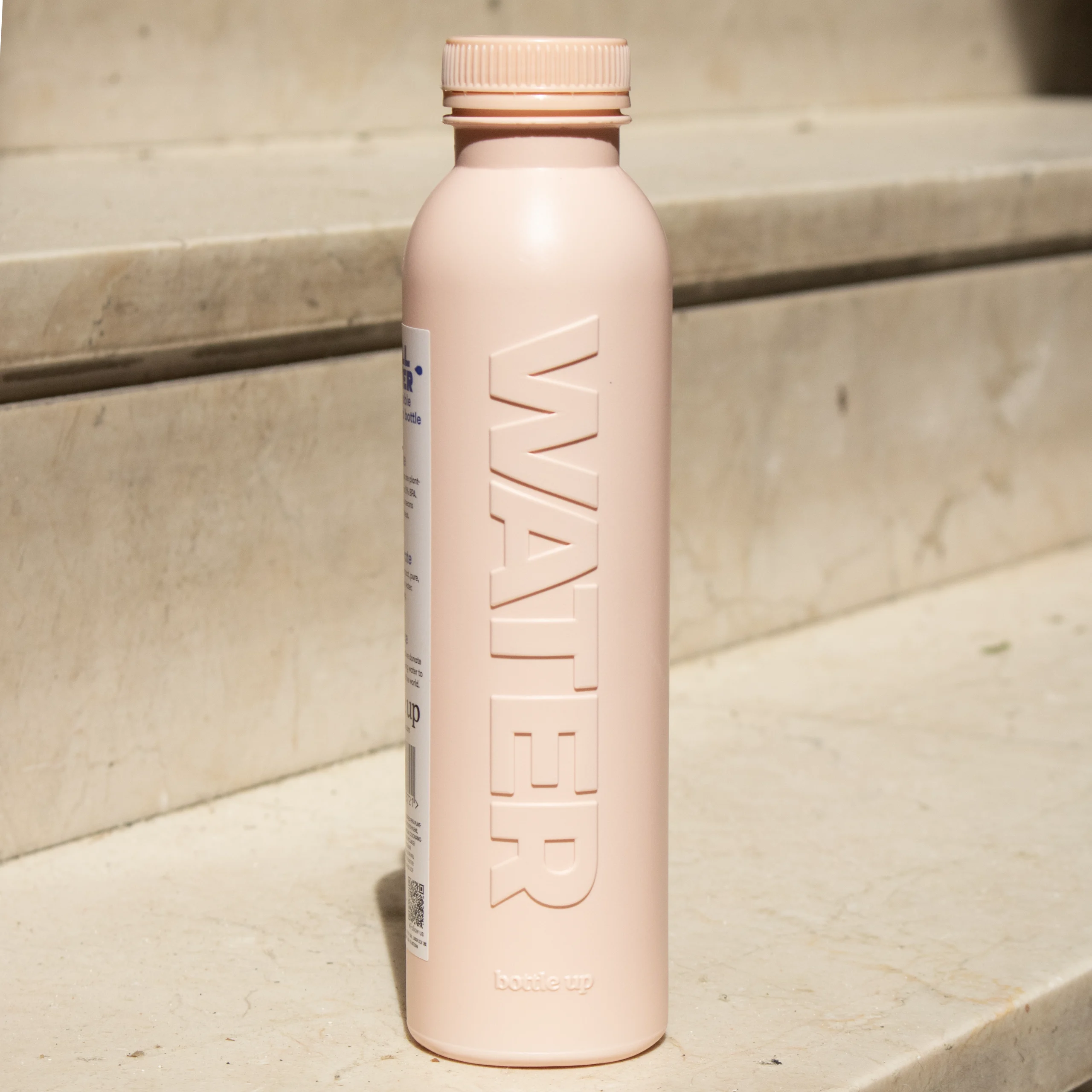 Botella rosa de caña de azúcar personalizada apoyada en una escalera de la calle