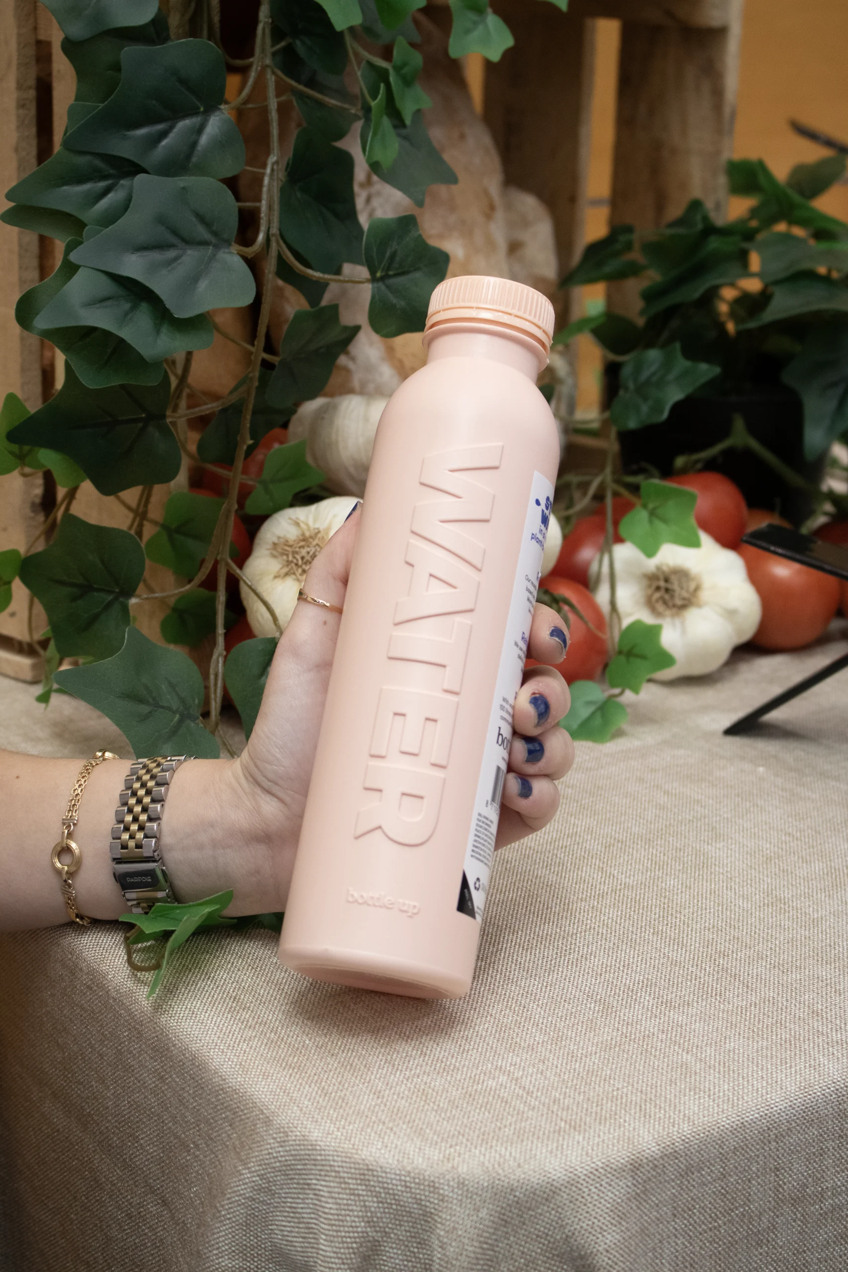 Mano sujetando una una botella de agua rosa personalizada en un evento de empresa