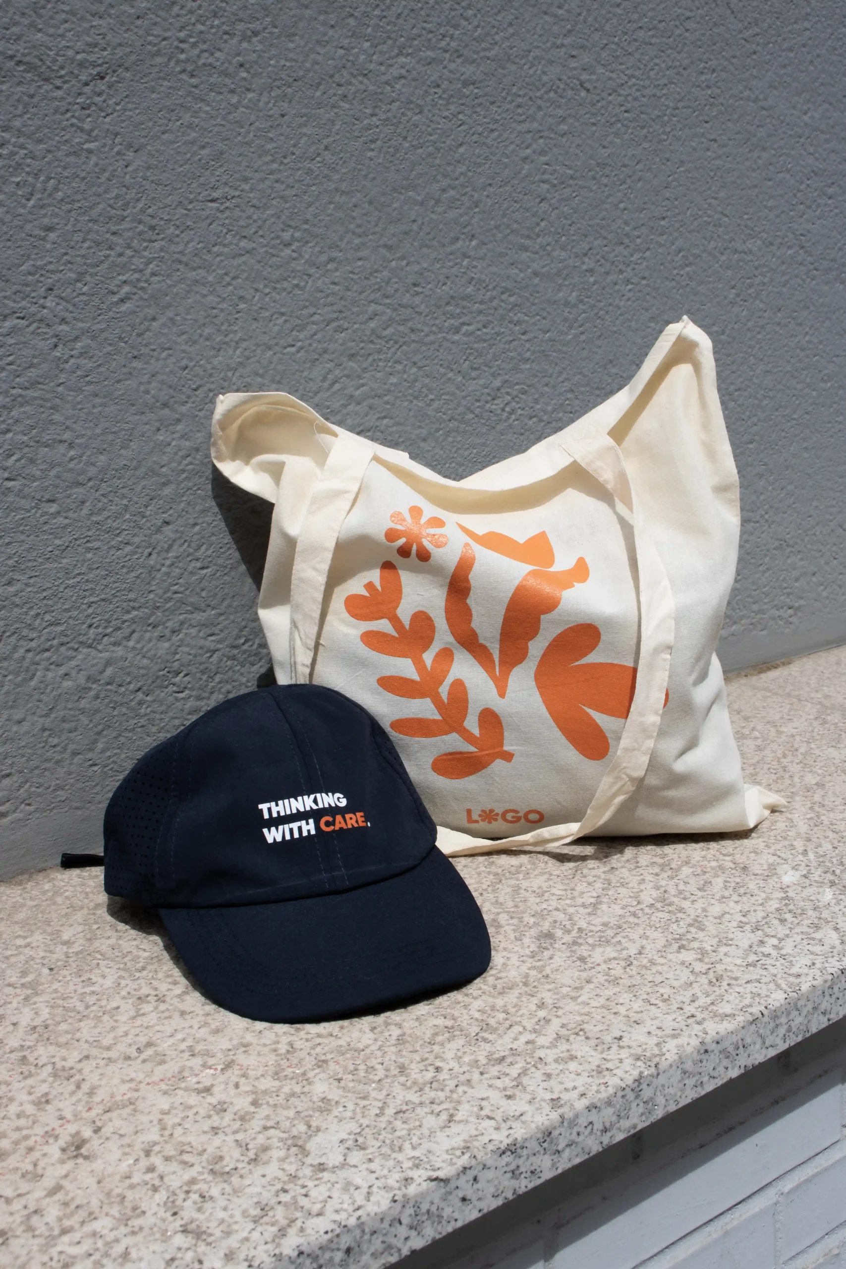 visera personalizada azul y tote bag algodón con logo naranja