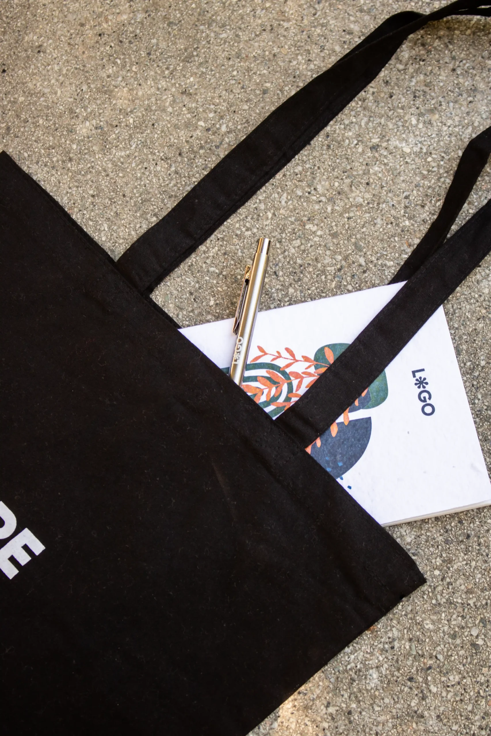 Bolsa negra de algodón con cuaderno personalizado y bolígrafo de aluminio reciclado