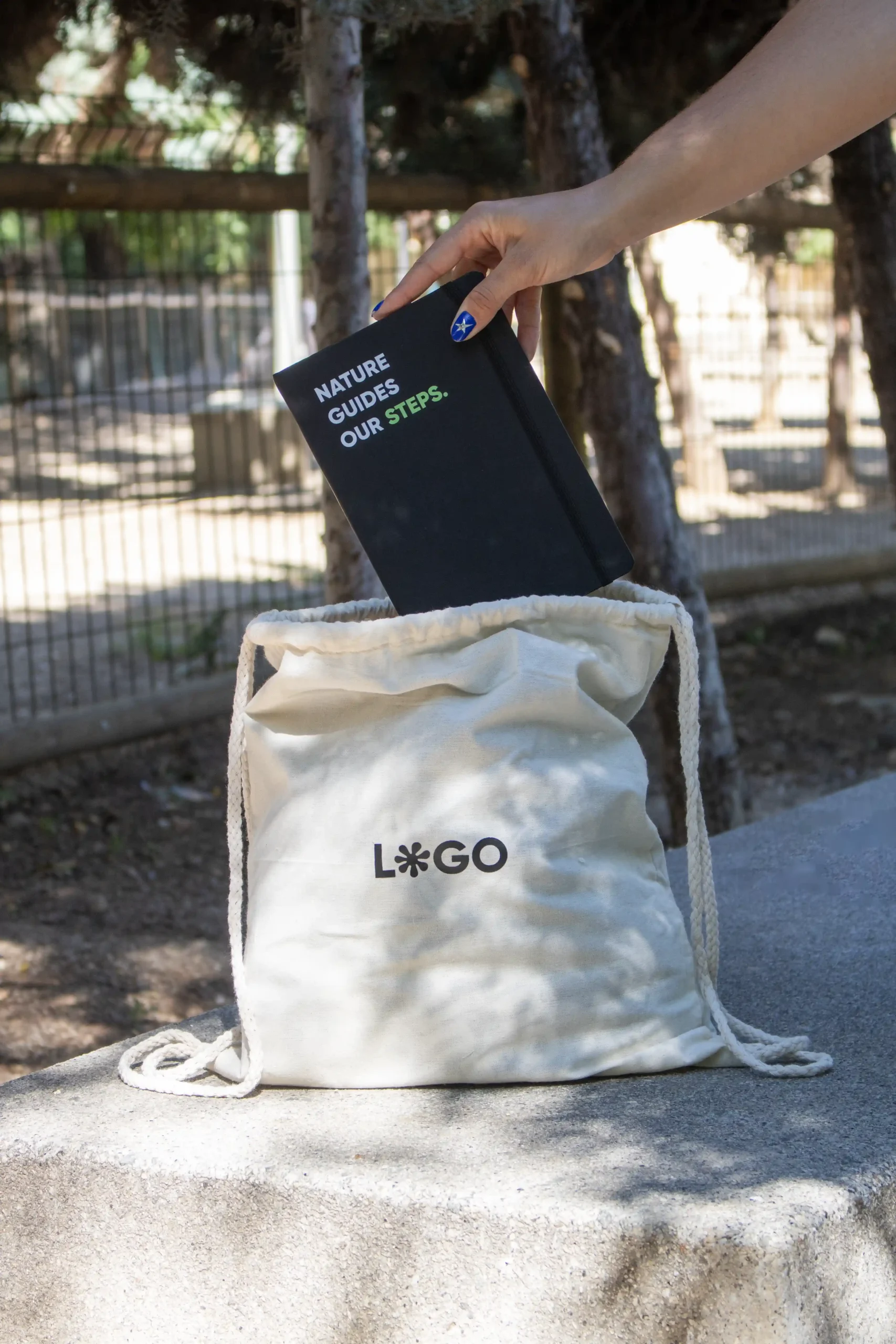 Mochila cuerdas personalizada tipo saco color beige con logo negro y cuaderno negro