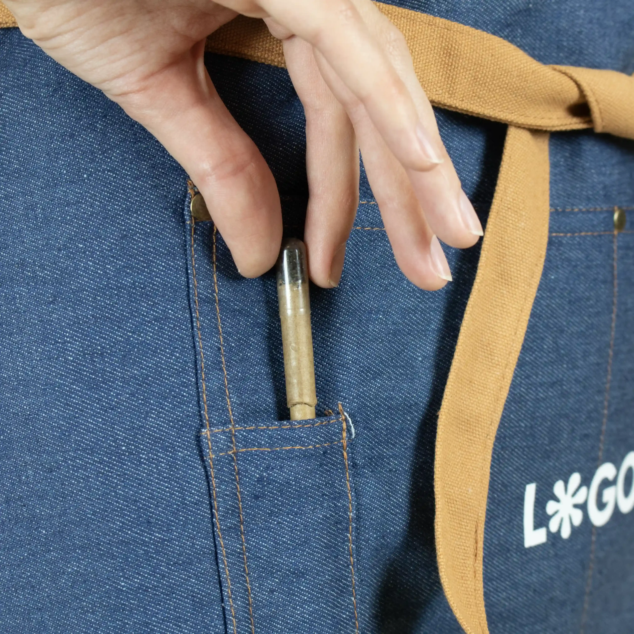 Delantal vaquero personalizado con logo blanco modelo chica detalle manos bolsillo