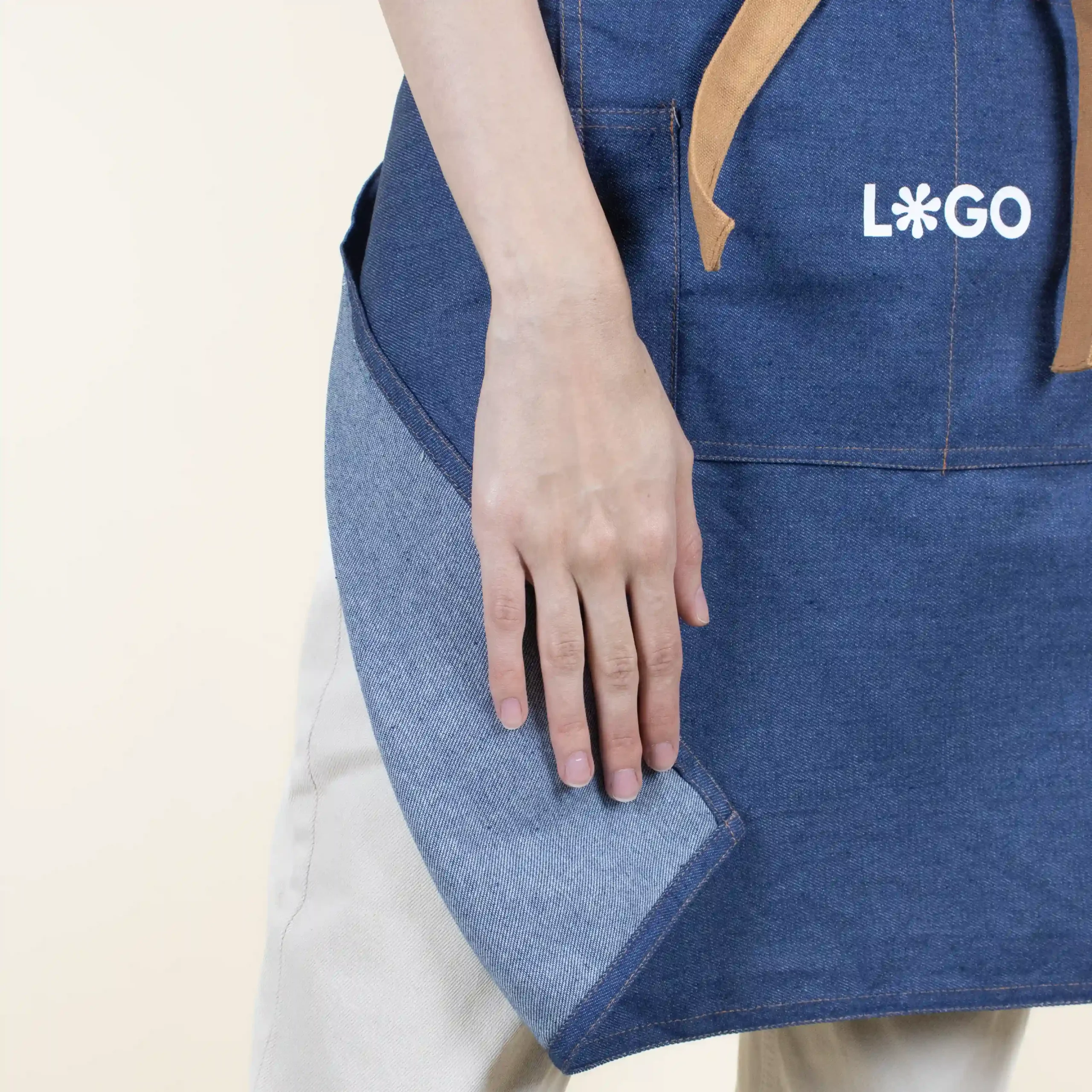 Delantal vaquero personalizado con logo blanco modelo chica detalle mano fondo beige