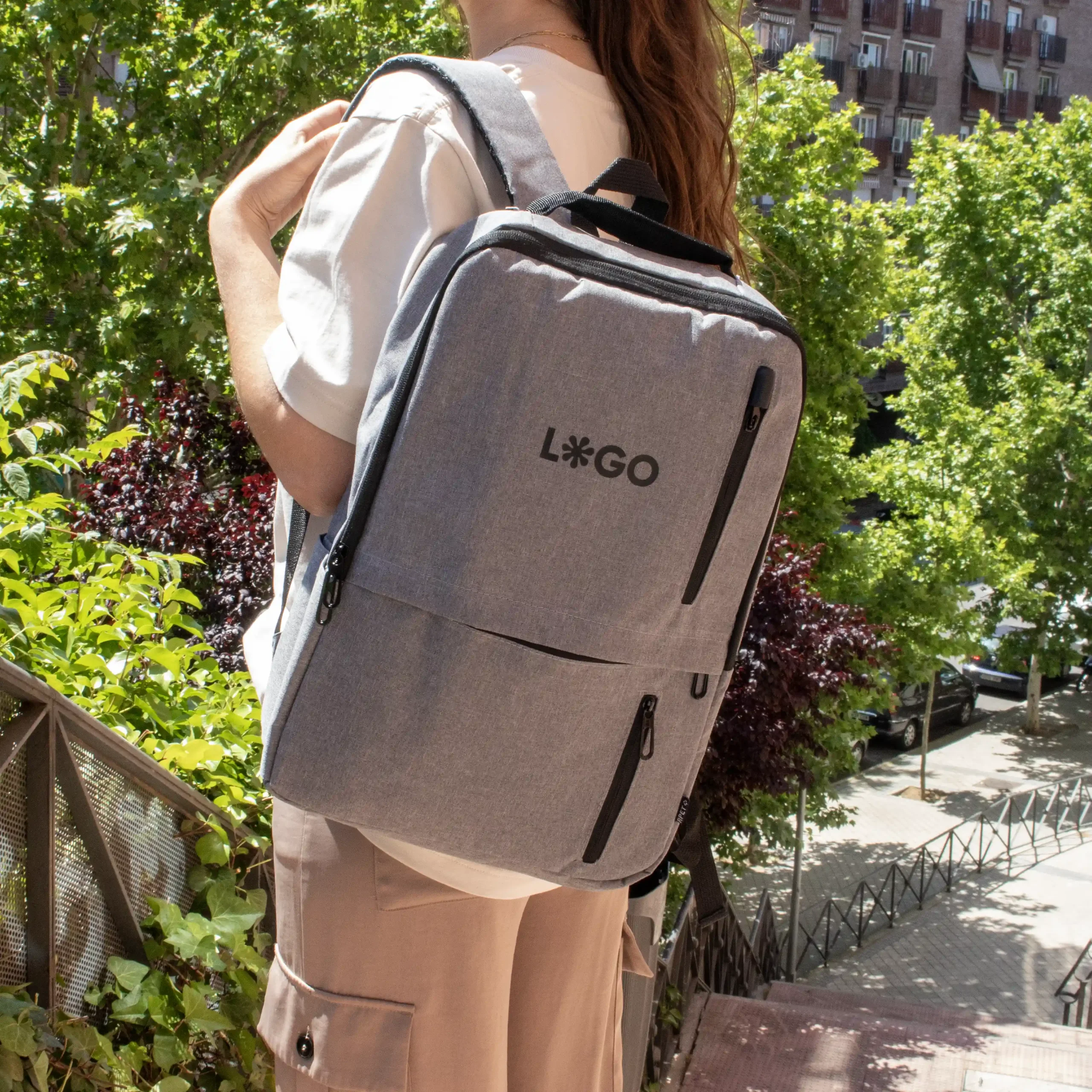 Mochila de empresa DUPPIA Gris Lifestyle Mochila de empresa personalizada gris con logo negro modelo chica en la calle