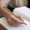 Mano escribiendo en cuaderno con bolígrafo marrón plantable con semillas