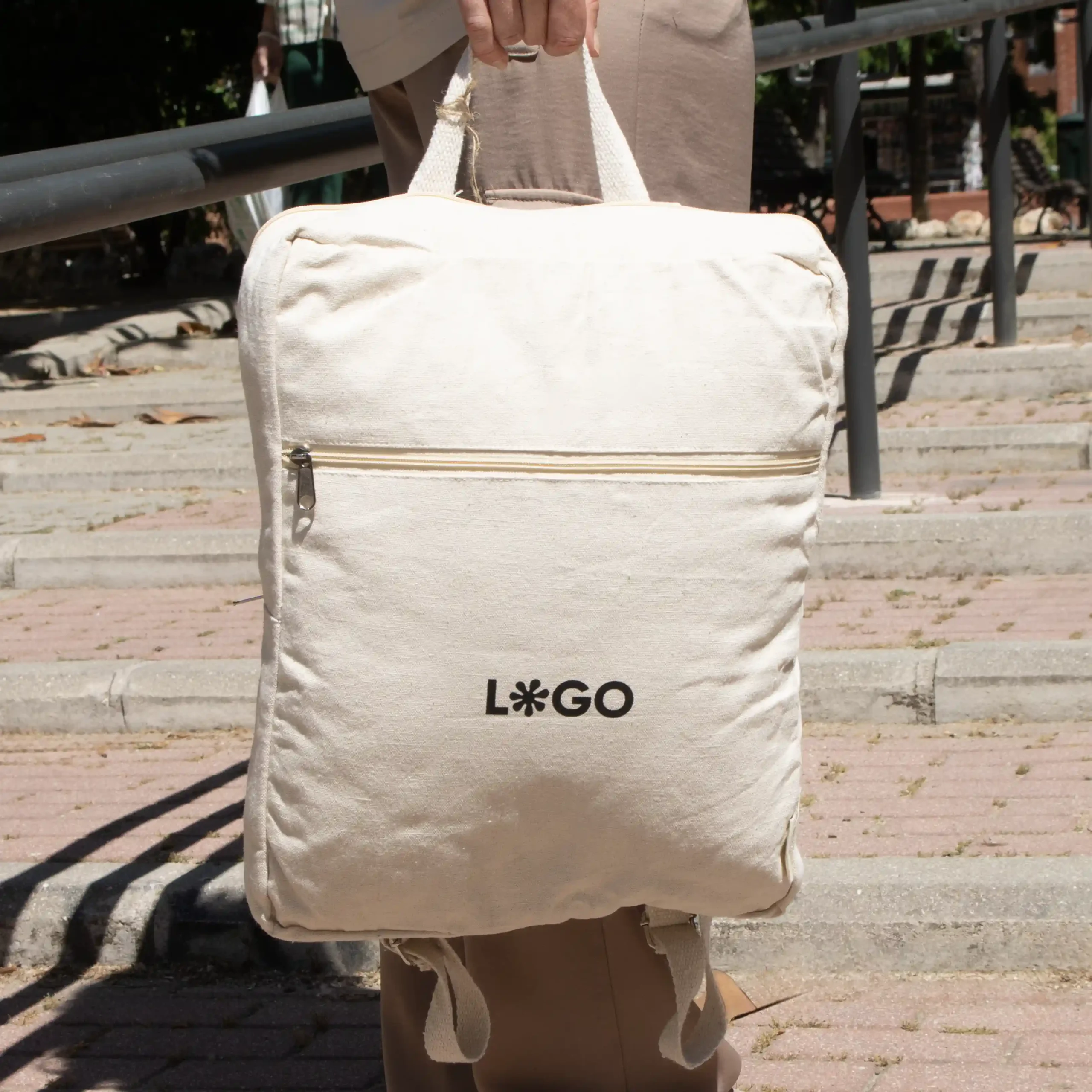 Mochila de algodón personalizada beige con logo negro modelo mano calle