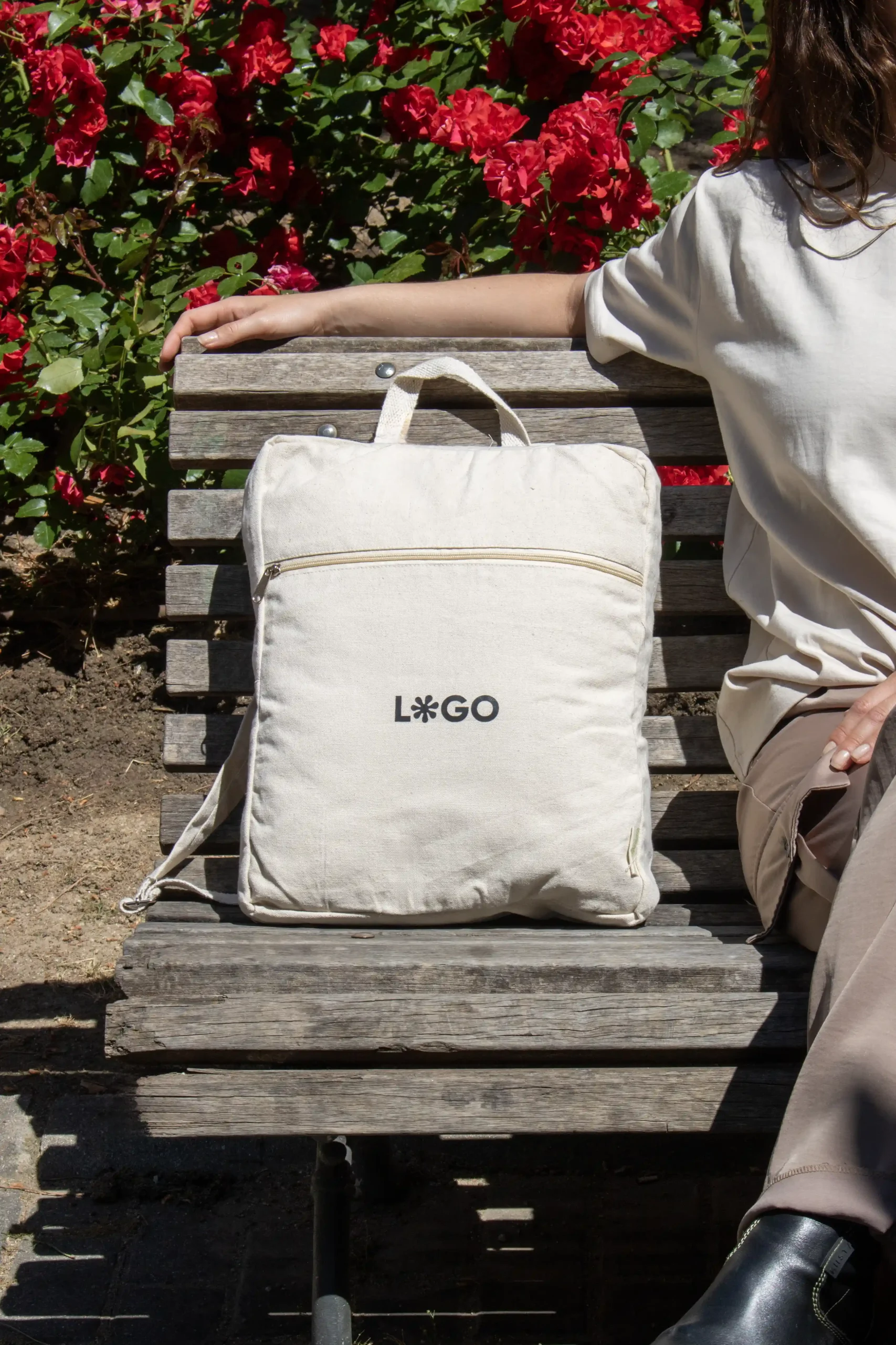 Mochila de algodón personalizada beige con logo negro modelo chica sentada en banco