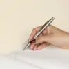 Mano escribiendo con bolígrafo de acero inoxidable personalizado