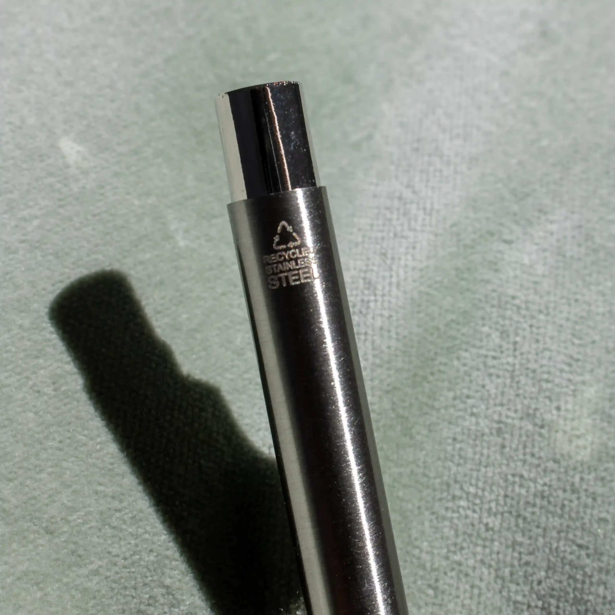 Bolígrafo de acero inoxidable reciclado sobre fondo verde