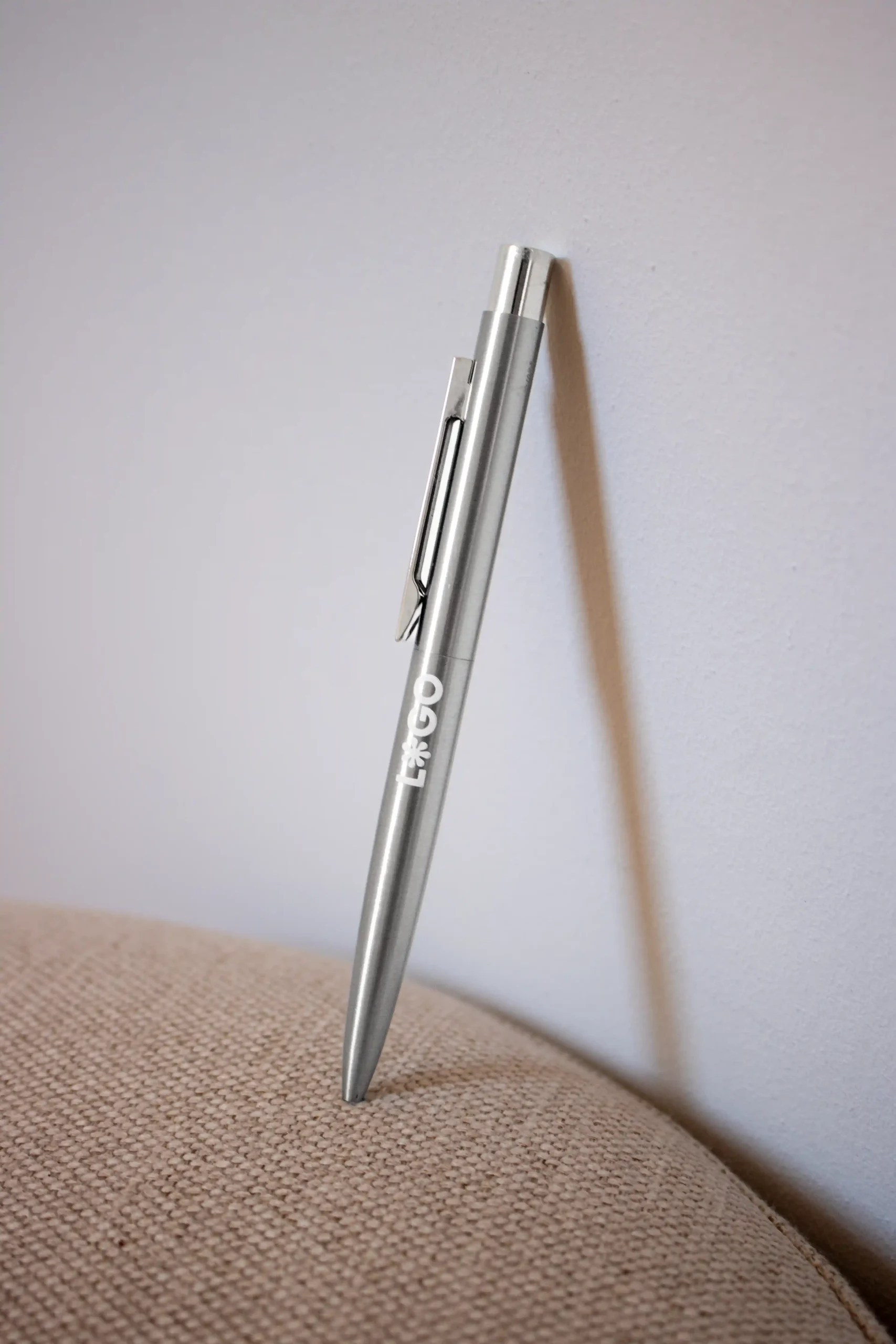Bolígrafo de acero inoxidable personalizado con logo apoyado en la pared