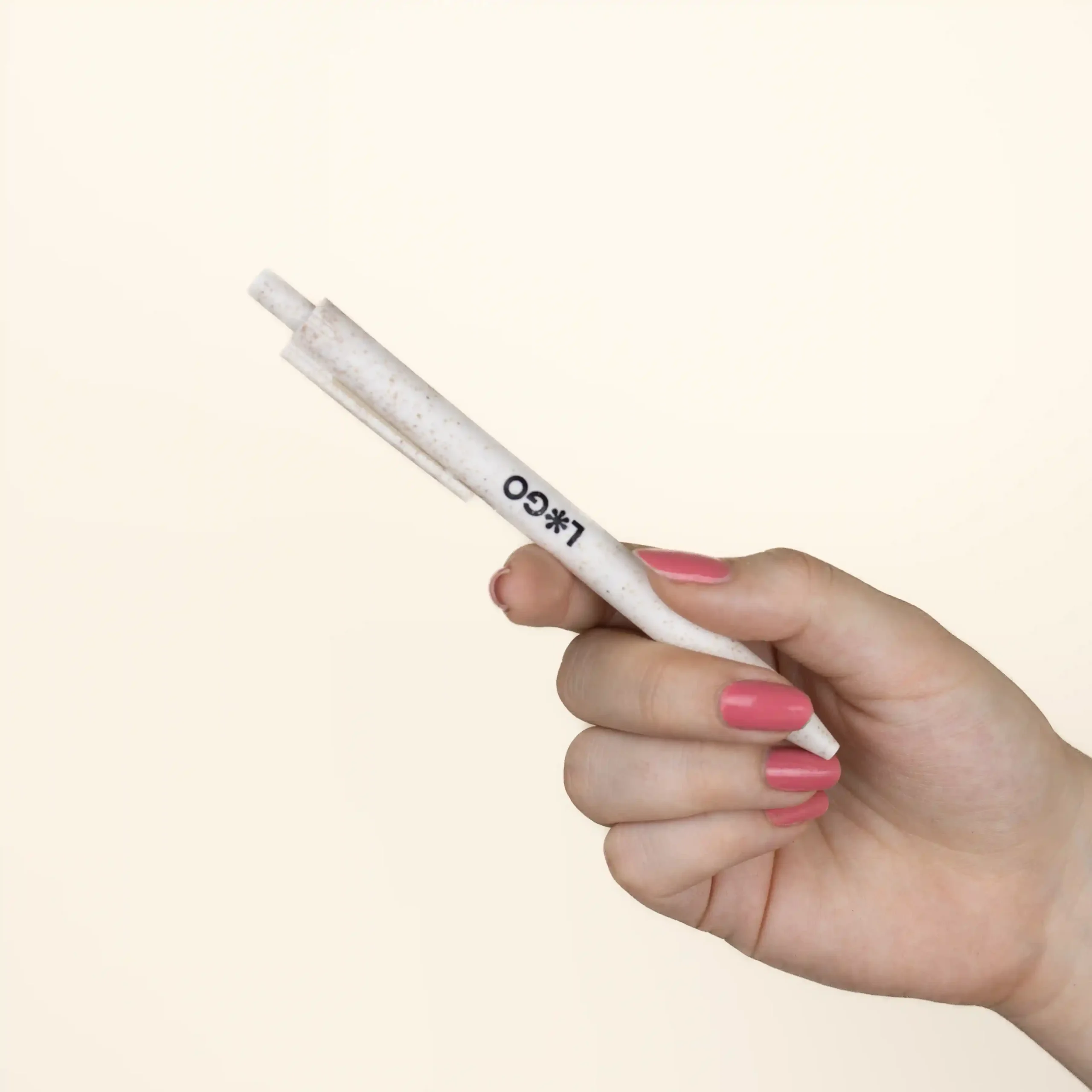 Bolígrafo trigo GLUT Beige Mano Mano sujetando bolígrafo de caña de trigo blanco personalizado con logo sobre fondo beige