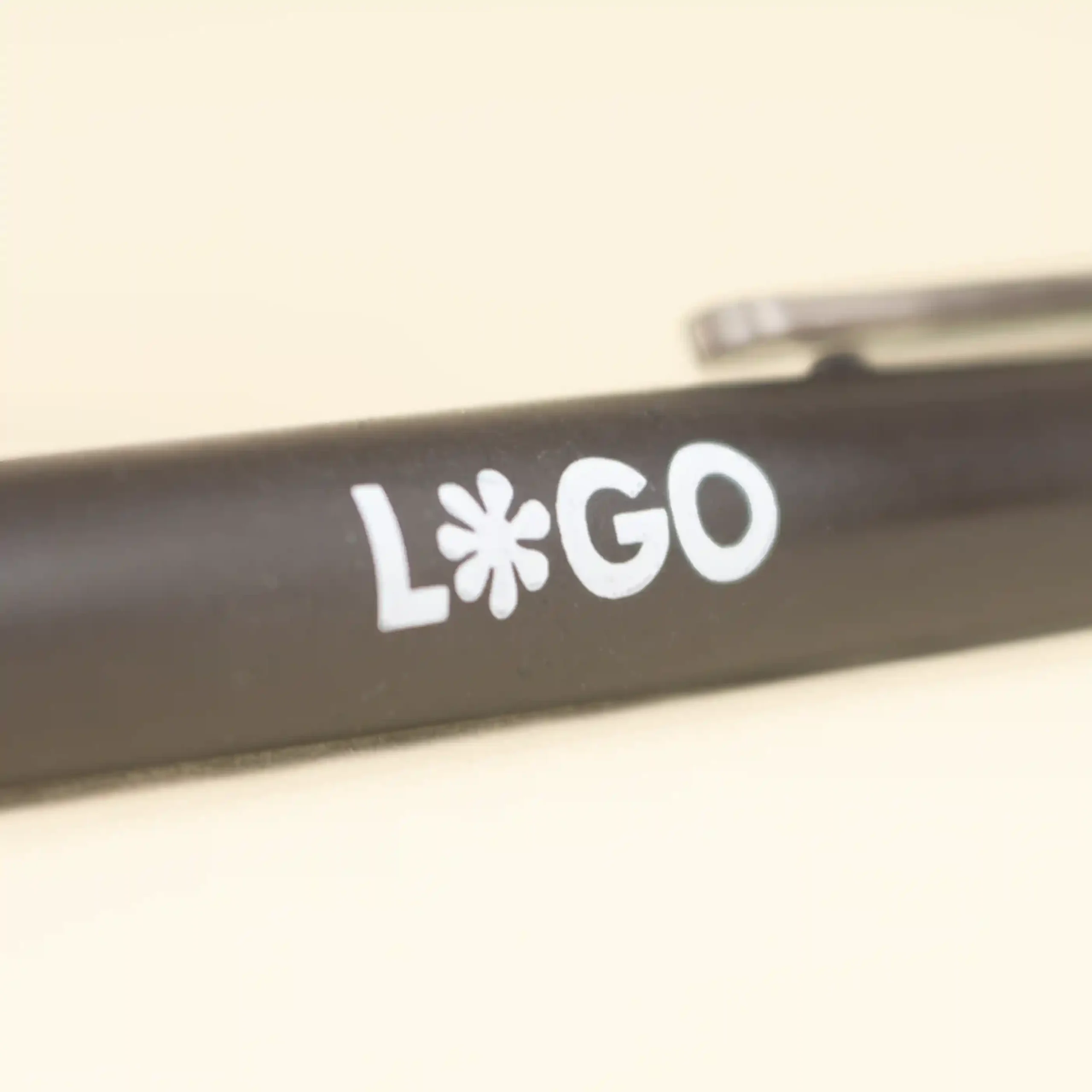 Cuerpo de bolígrafo marrón de fibra de cafe personalizado con logo blanco sobre fondo beige