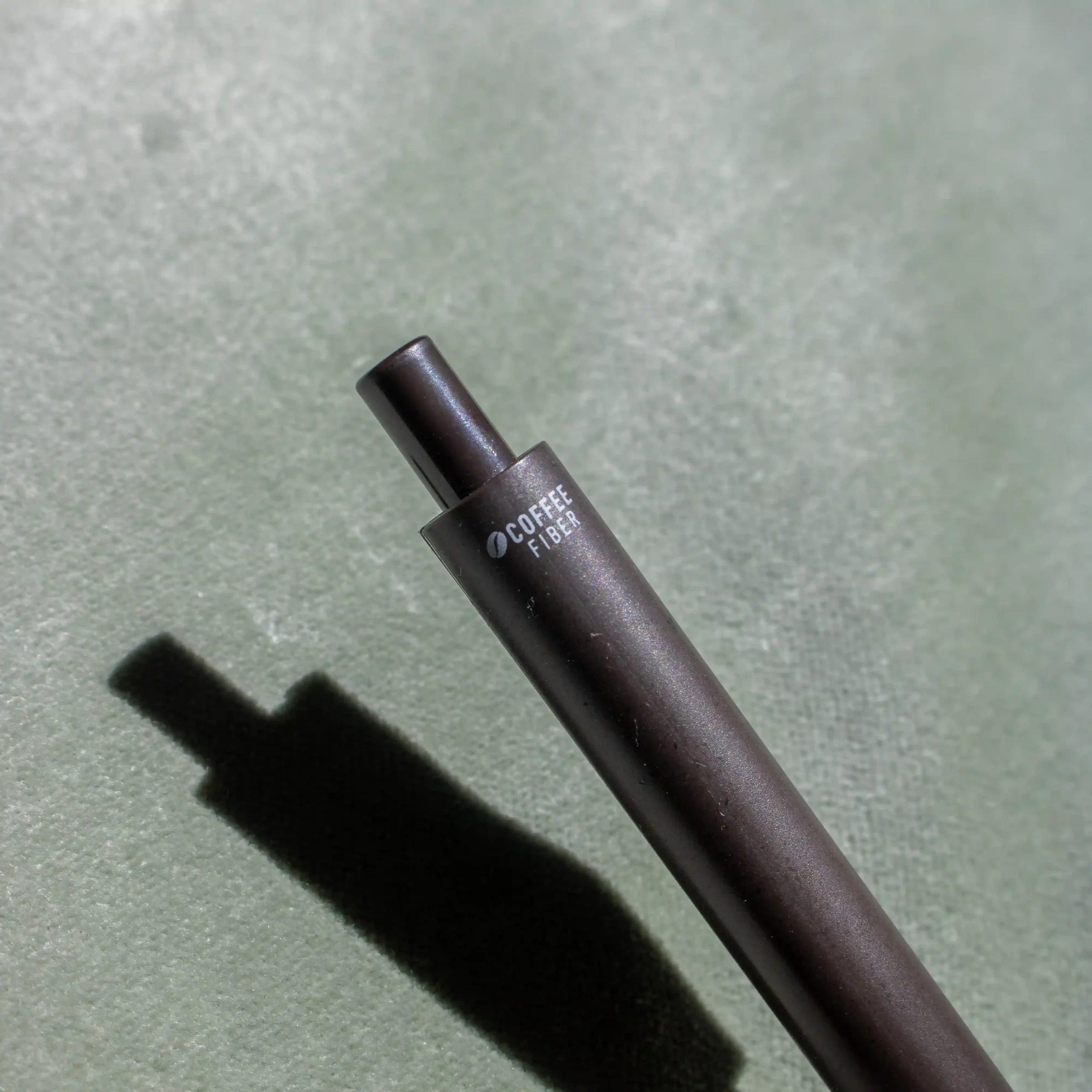 Pulsador de bolígrafo marrón de fibra de cafe sobre fondo verde