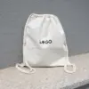 Mochila cuerdas personalizada tipo saco color beige con logo negro fondo gris