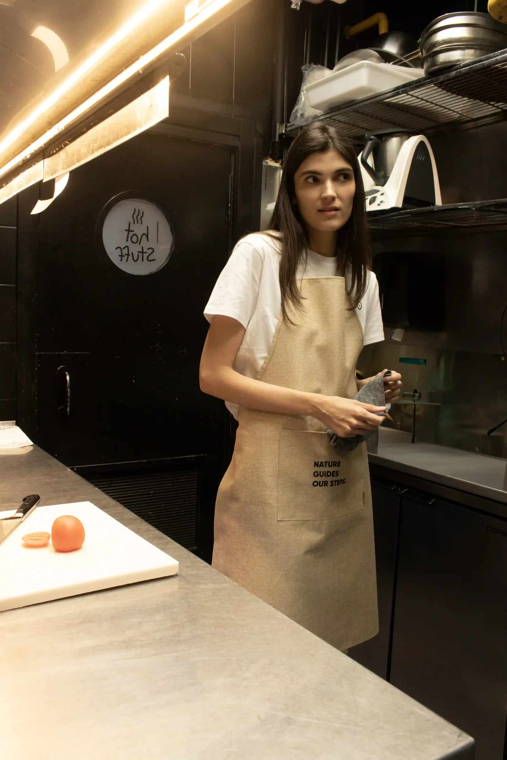 Delantal ecológico beige modelo chica en cocina de restaurante